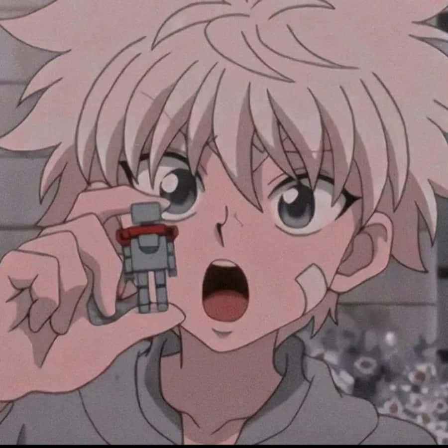 Killua Pfp 桌布 壁紙 — 一個驚訝的動畫男孩，有著尖刺的粉紅色頭髮，將一個小型機器人玩具舉到眼前。