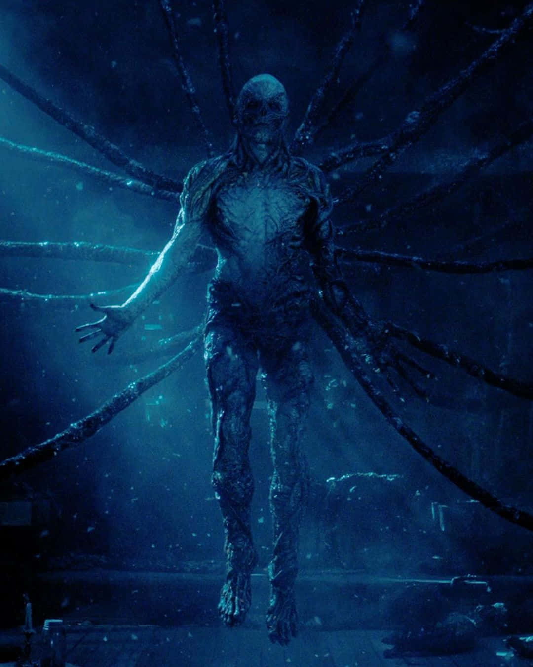  壁紙 — 一個高大、怪誕的人形生物，有多條扭動的觸手，從黑暗冰冷的水下深淵中浮現，沐浴在詭異的藍光中。