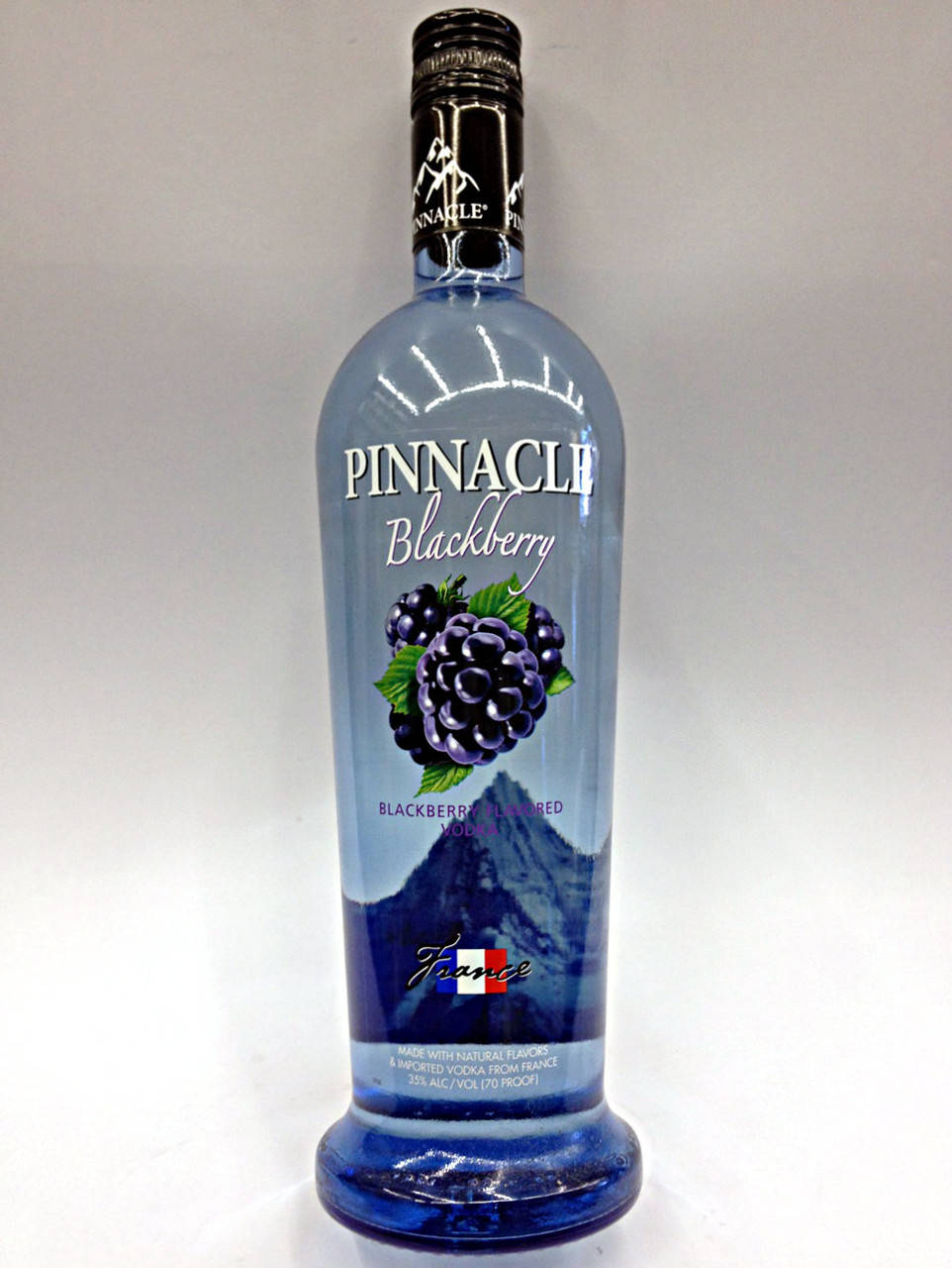 bottle 桌布 壁紙 — 一個高大的藍色 Pinnacle Blackberry 伏特加酒瓶，置於純白色背景中央，帶有清晰的標籤和黑莓插圖。