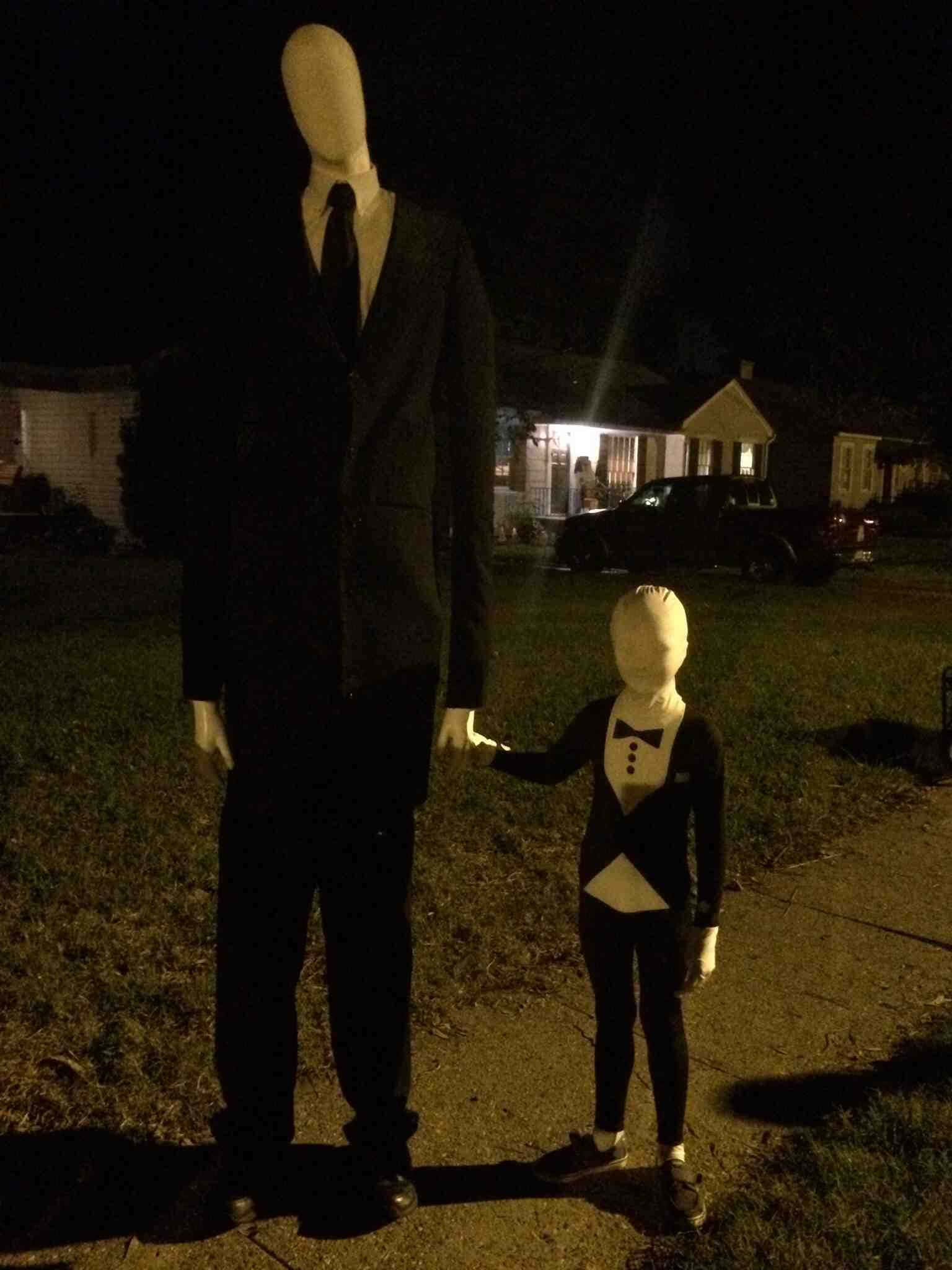 Creepypasta 桌布 壁紙 — 一個高大的西裝模特兒在夜間街燈下，與一個穿著相配燕尾服的小孩手牽手。