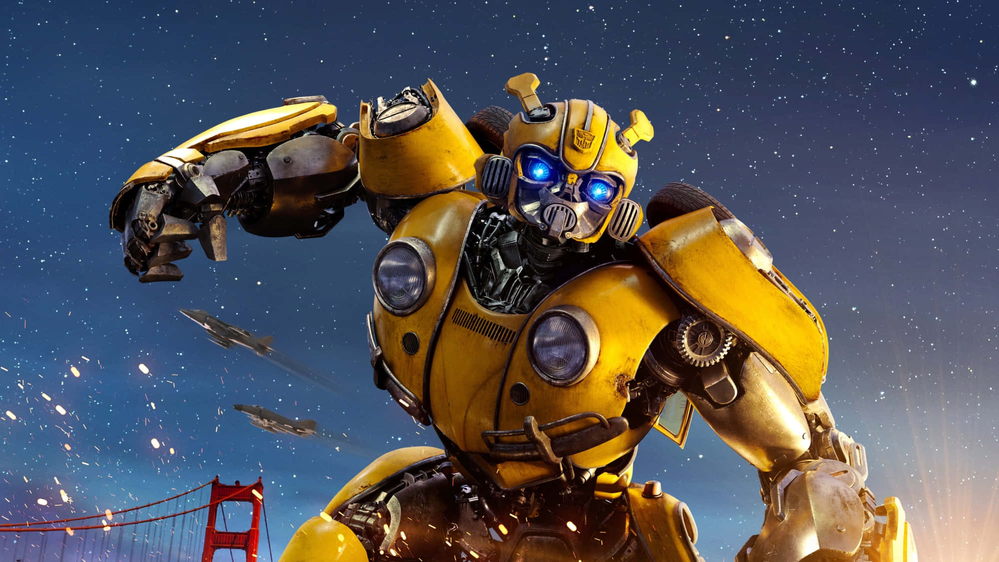Bumblebee 桌布 壁紙 — 一個高大的黃色機器人，藍色眼睛發光，英雄般地站在繁星點點的夜空下，火花四濺，背景是金門大橋。