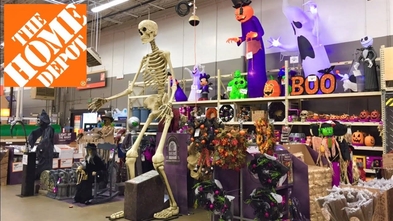 Home Depot 桌布 壁紙 — 一個高聳的骷髏在Home Depot的通道上站崗，通道上堆滿了色彩繽紛的萬聖節裝飾和服裝。