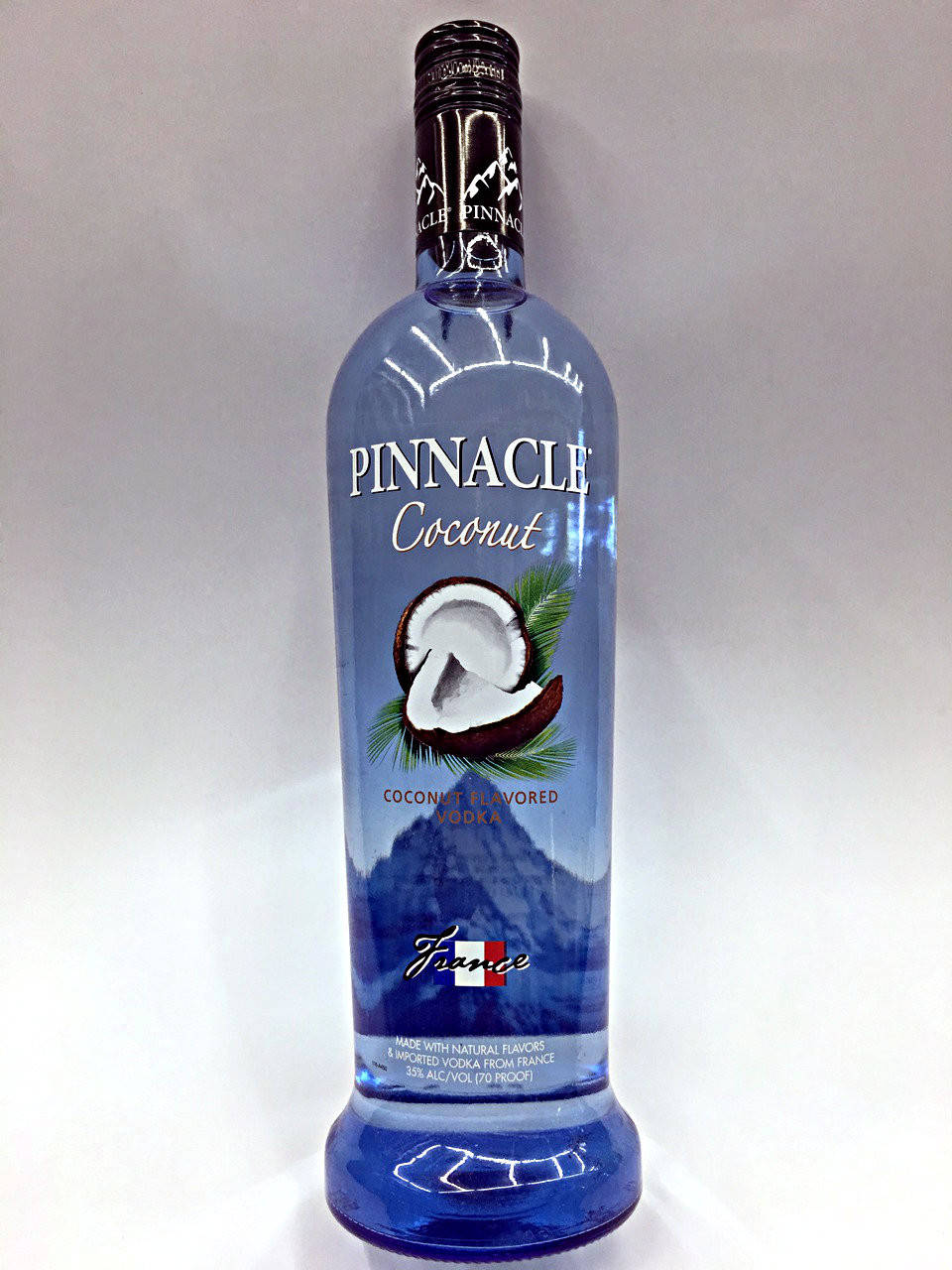 bottle 桌布 壁紙 — 一個高藍色瓶的Pinnacle Coconut伏特加，置於純白色背景中央，帶有清晰標籤和椰子圖案。