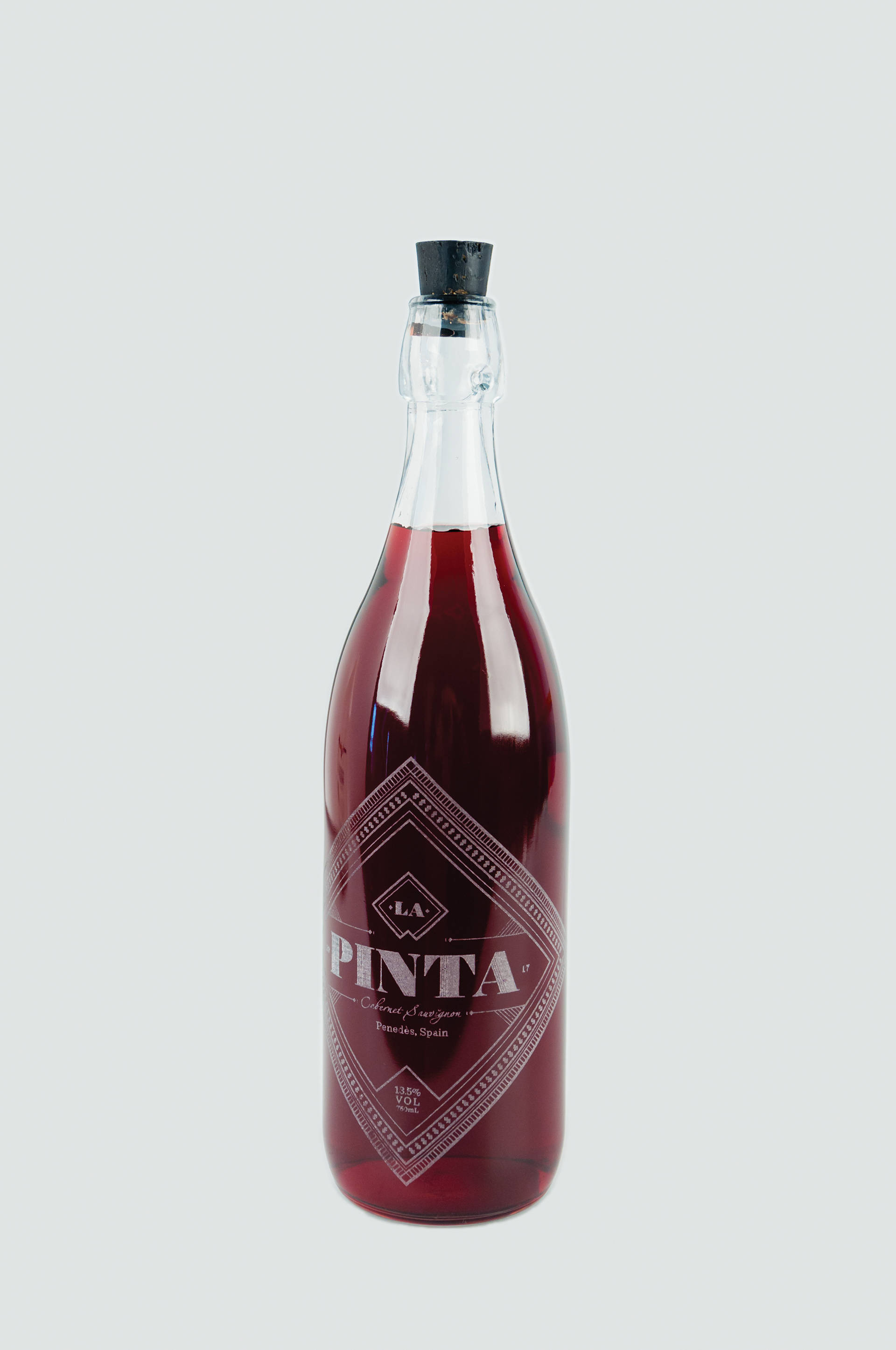 bottle 桌布 壁紙 — 一個高身玻璃瓶，裝滿深紅色液體，配有黑色軟木塞，置於淺灰色背景上。