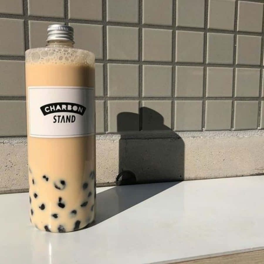 Boba Tea 桌布 壁紙 — 一個高身的珍珠奶茶瓶，裡面有黑色珍珠，放在白色表面上，對著磁磚牆，在明亮的陽光下。