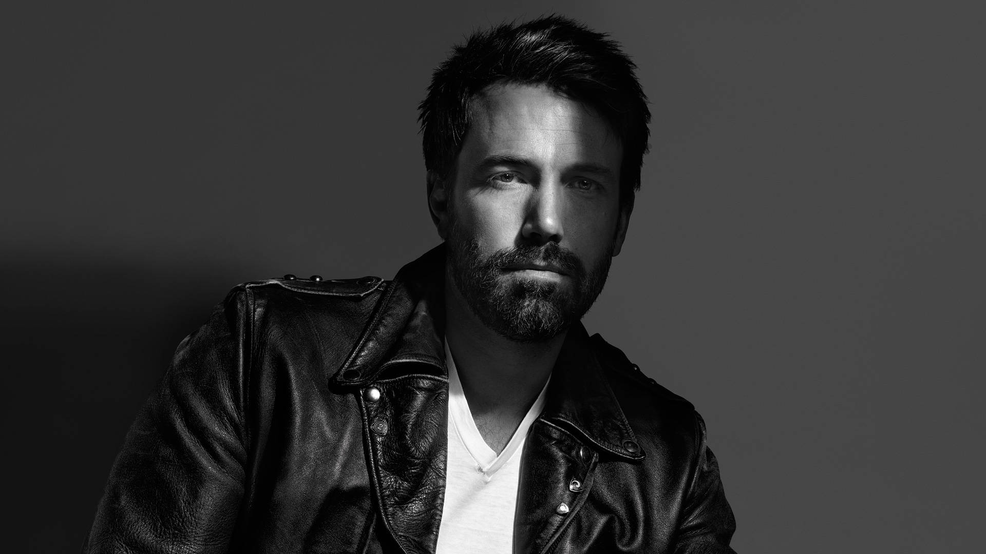Ben Affleck 桌布 壁紙 — 一個鬍鬚男穿著皮夾克的黑白肖像，背景是純灰色。