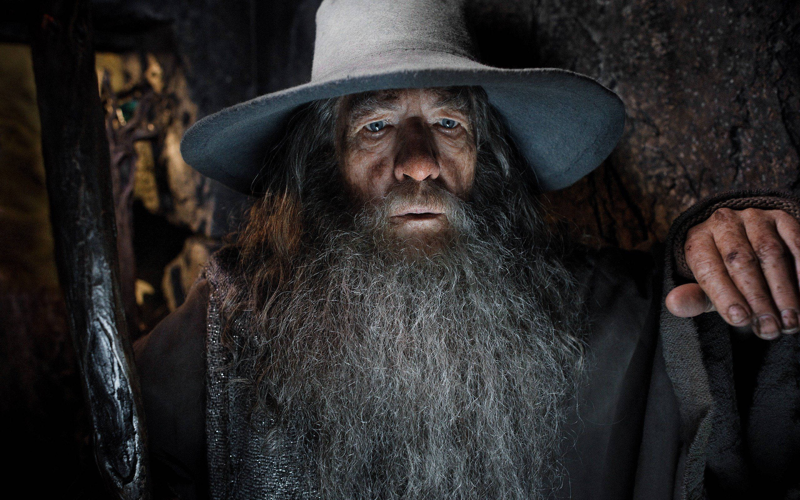 Gandalf 桌布 壁紙 — 一個鬍鬚矮人戴著寬邊帽在昏暗洞穴中的特寫。