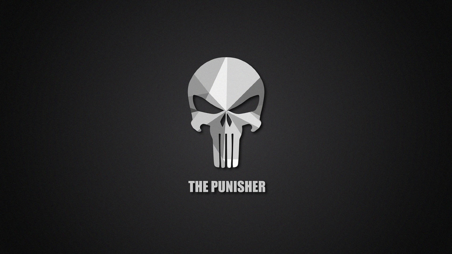 Punisher Logo 桌布 壁紙 — 一個鮮明的幾何骷髏標誌，帶有銳利的銀色切面，居中於深灰色漸變背景上，下方有粗體白色文字。