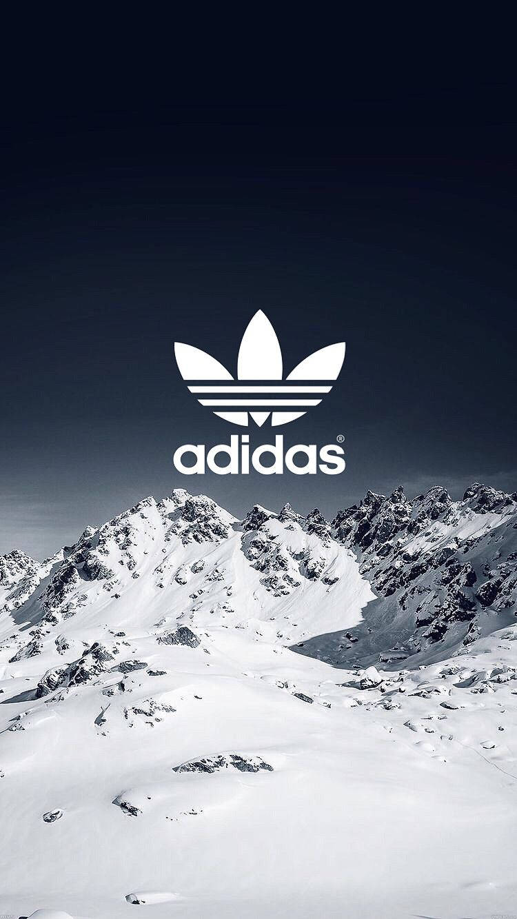 愛迪達 桌布 壁紙 — 一個鮮明的白色adidas標誌漂浮在白雪覆蓋的山脈之上，背景是深藍色的天空。