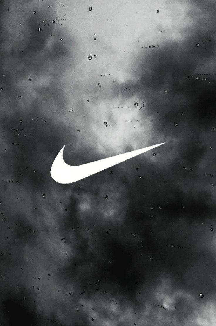 Nike 桌布 壁紙 — 一個鮮明的白色Nike swoosh標誌在充滿氣氛的單色天空中發光，天空中有雨滴和漩渦狀的雲層。