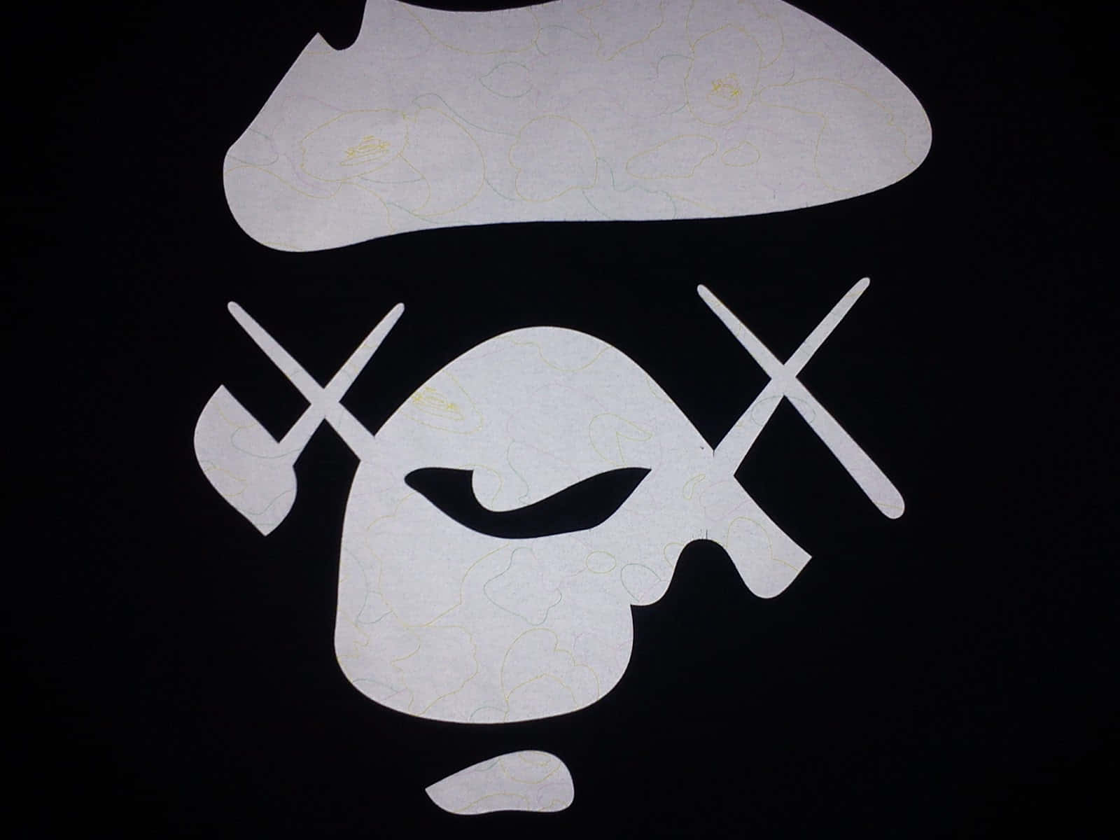 Bape 動態 桌布 壁紙 — 一個鮮明的白色紙剪影，風格化的海盜骷髏頭，交叉骨頭和帽子，在黑色背景上。