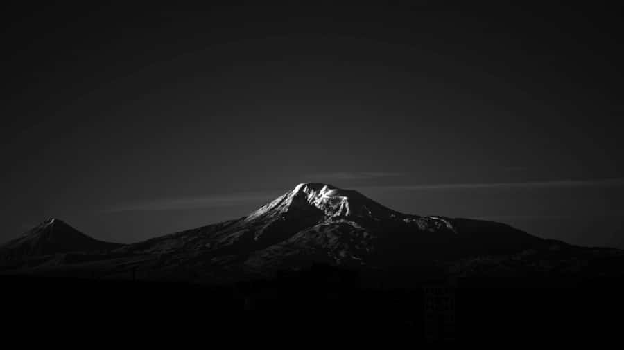 1366x768 Amoled 桌布 壁紙 — 一個鮮明的黑白山峰剪影，山頂積雪在漸變的天空中閃耀。