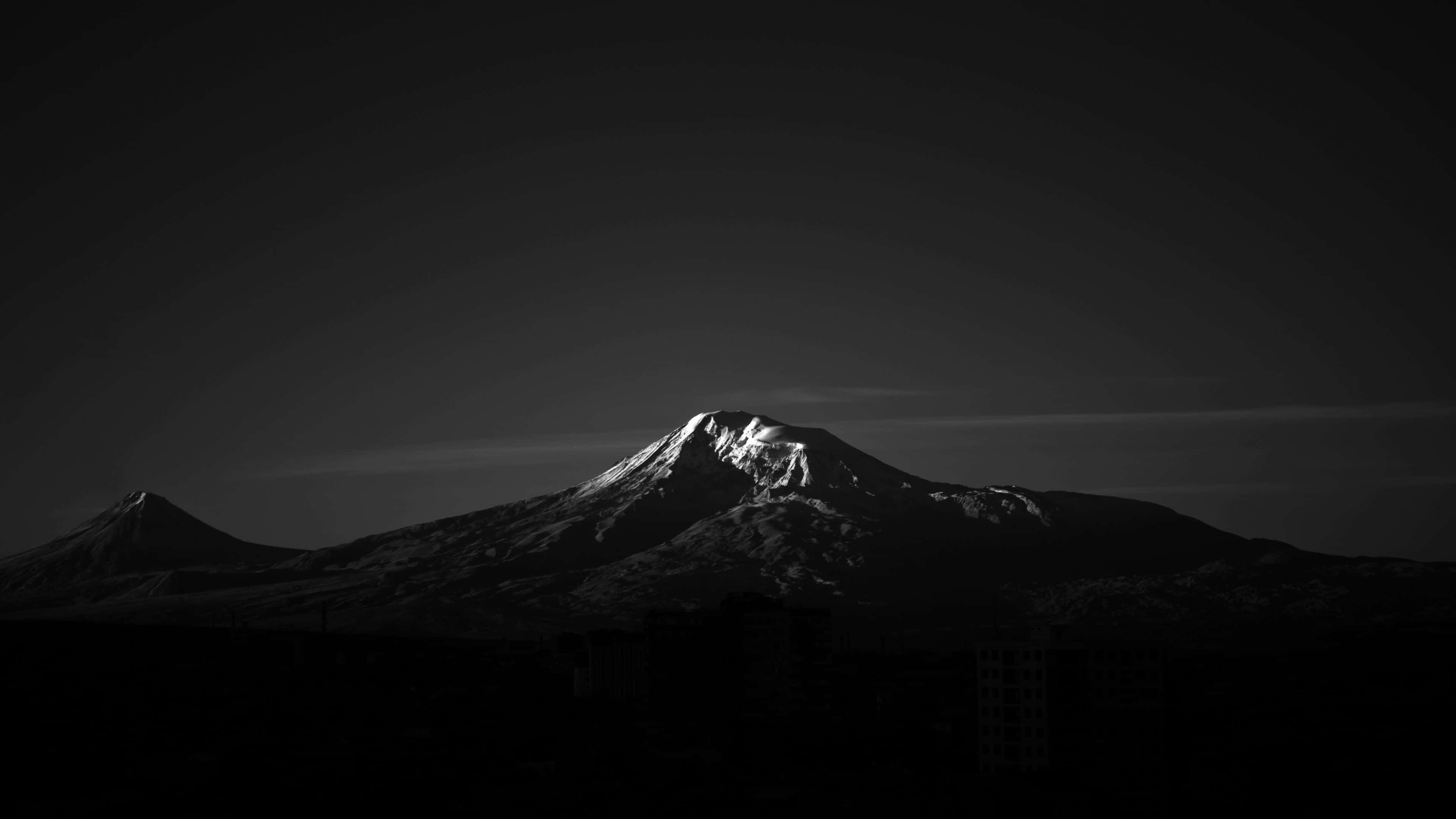 背景 桌布 壁紙 — 一個鮮明的黑白山峰剪影，雪覆蓋的山頂在黑暗的天空中閃耀。