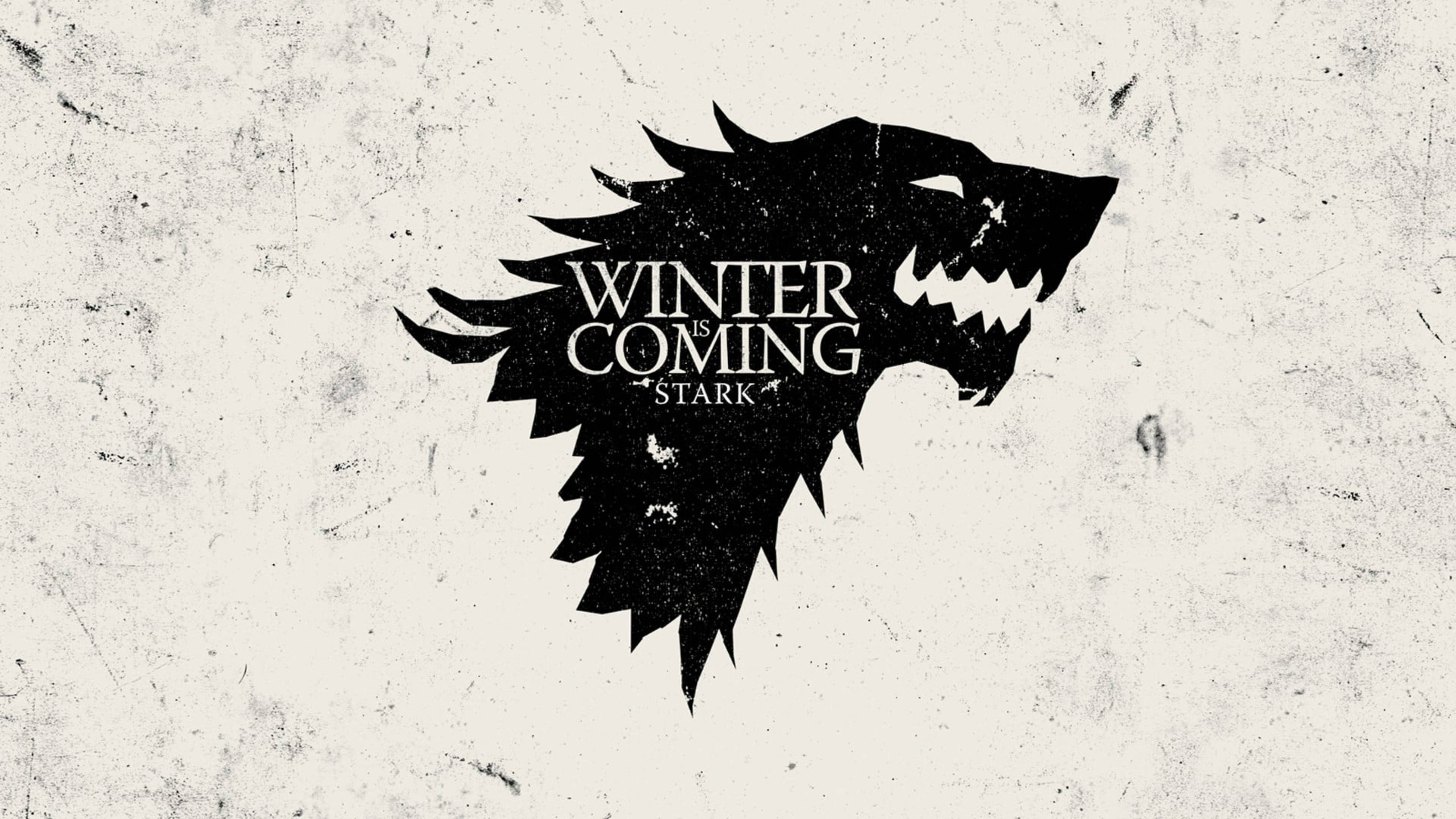 House Stark 桌布 壁紙 — 一個鮮明的黑色冰原狼頭標誌，上面有「WINTER IS COMING STARK」文字，背景是風化的米白色。