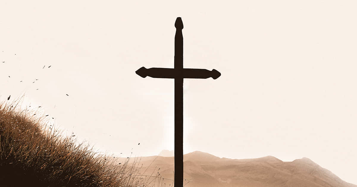 Lent 桌布 壁紙 — 一個鮮明的黑色十字架，在青草覆蓋的山丘頂上，以蒼白的天空為背景，襯托出剪影，遠方有山巒。