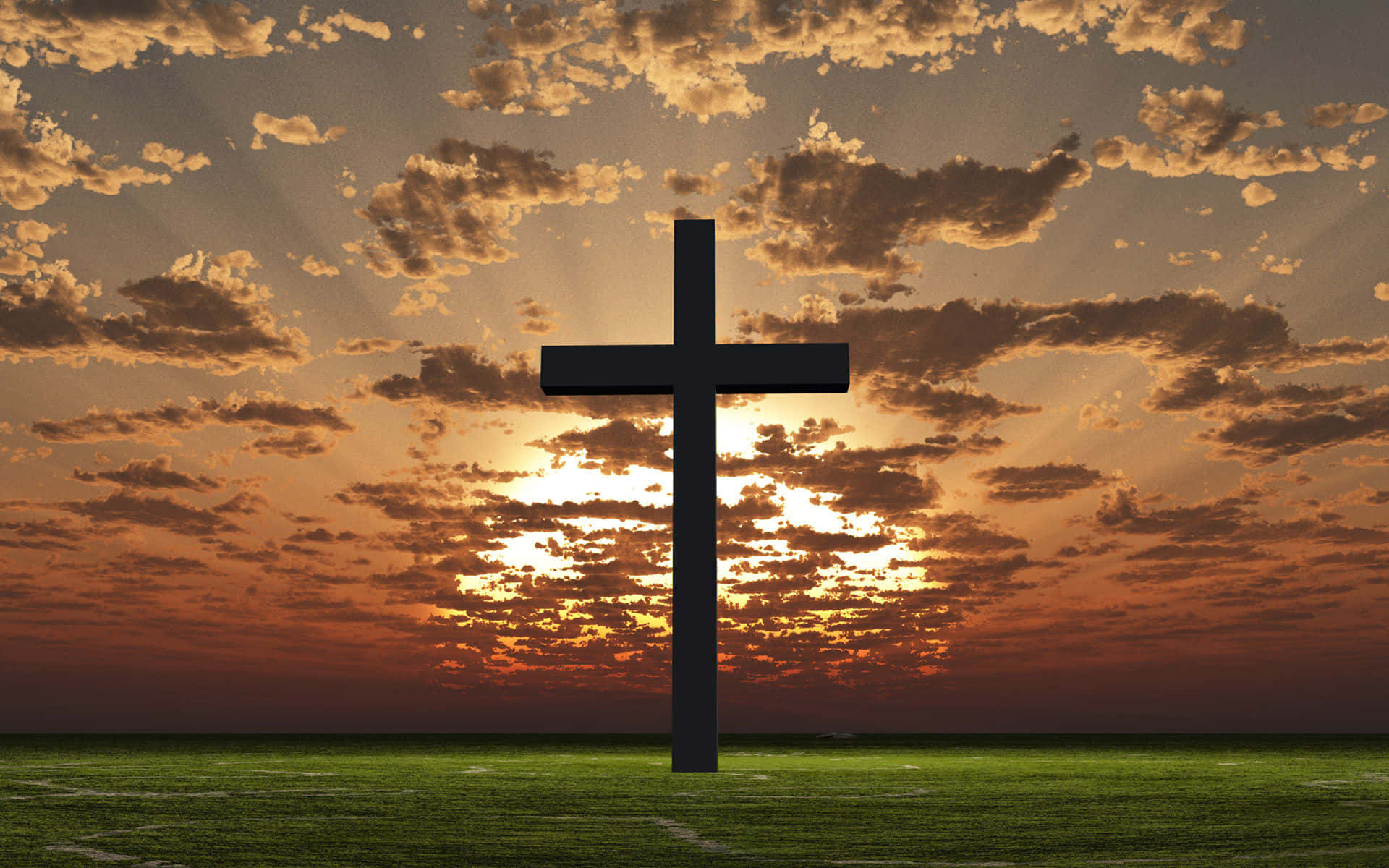 Catholic Desktop 桌布 壁紙 — 一個鮮明的黑色十字架獨自矗立在充滿活力的綠色田野上，背景是帶有金色雲彩的戲劇性日落天空。