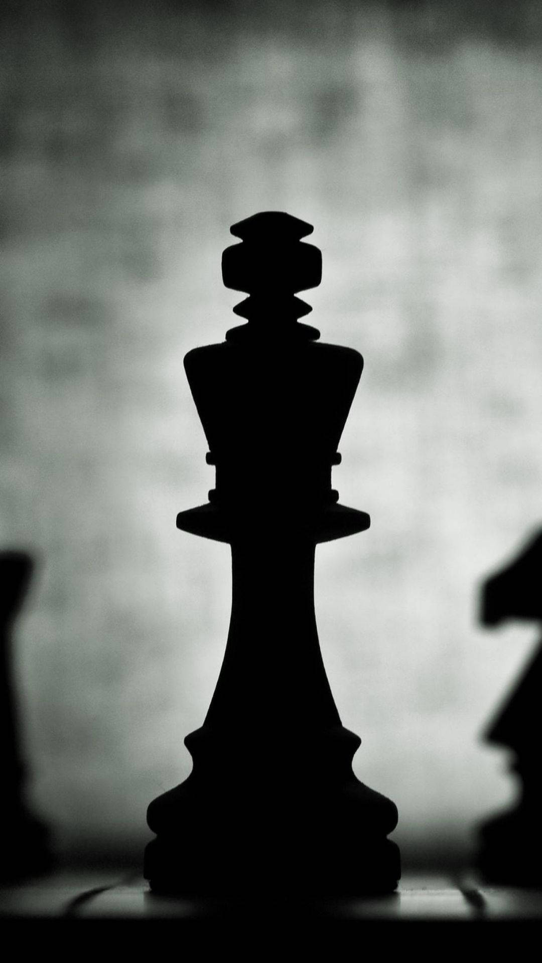 棋盤上國王棋子的剪影，背景中有模糊的棋子。