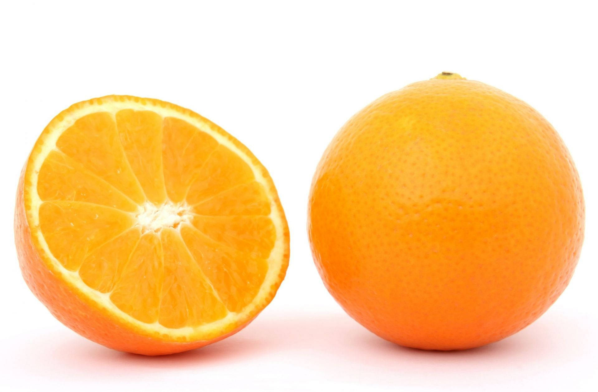 Fruits 桌布 壁紙 — 一個鮮橙切半，旁邊放著一個完整橙，在潔白背景上。