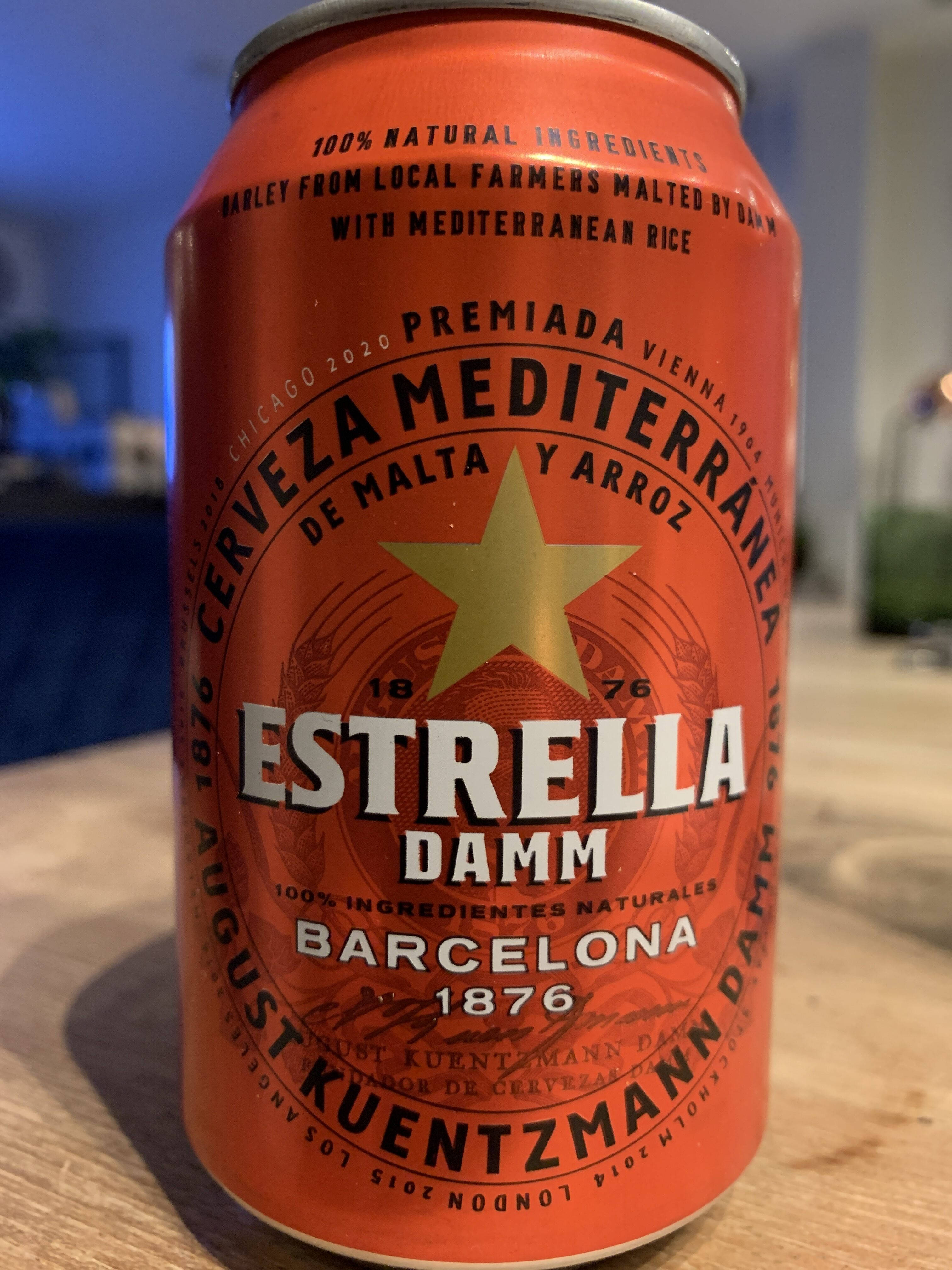 alcohol 桌布 壁紙 — 一個鮮橙色的Estrella Damm啤酒罐，上面有金色星星標誌，放在一個柔和燈光的室內木質表面上。