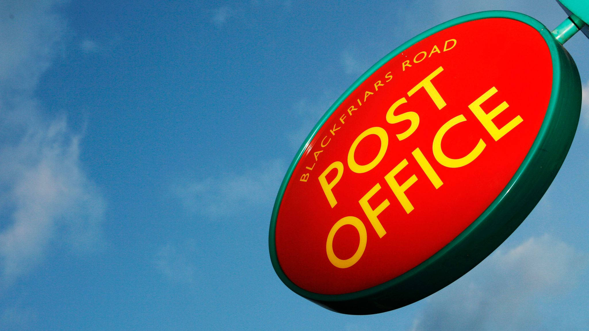 Post Office 桌布 壁紙 — 一個鮮紅色橢圓形郵政局標誌，上面有黃色字體，掛在晴朗藍天和薄雲的背景中。
