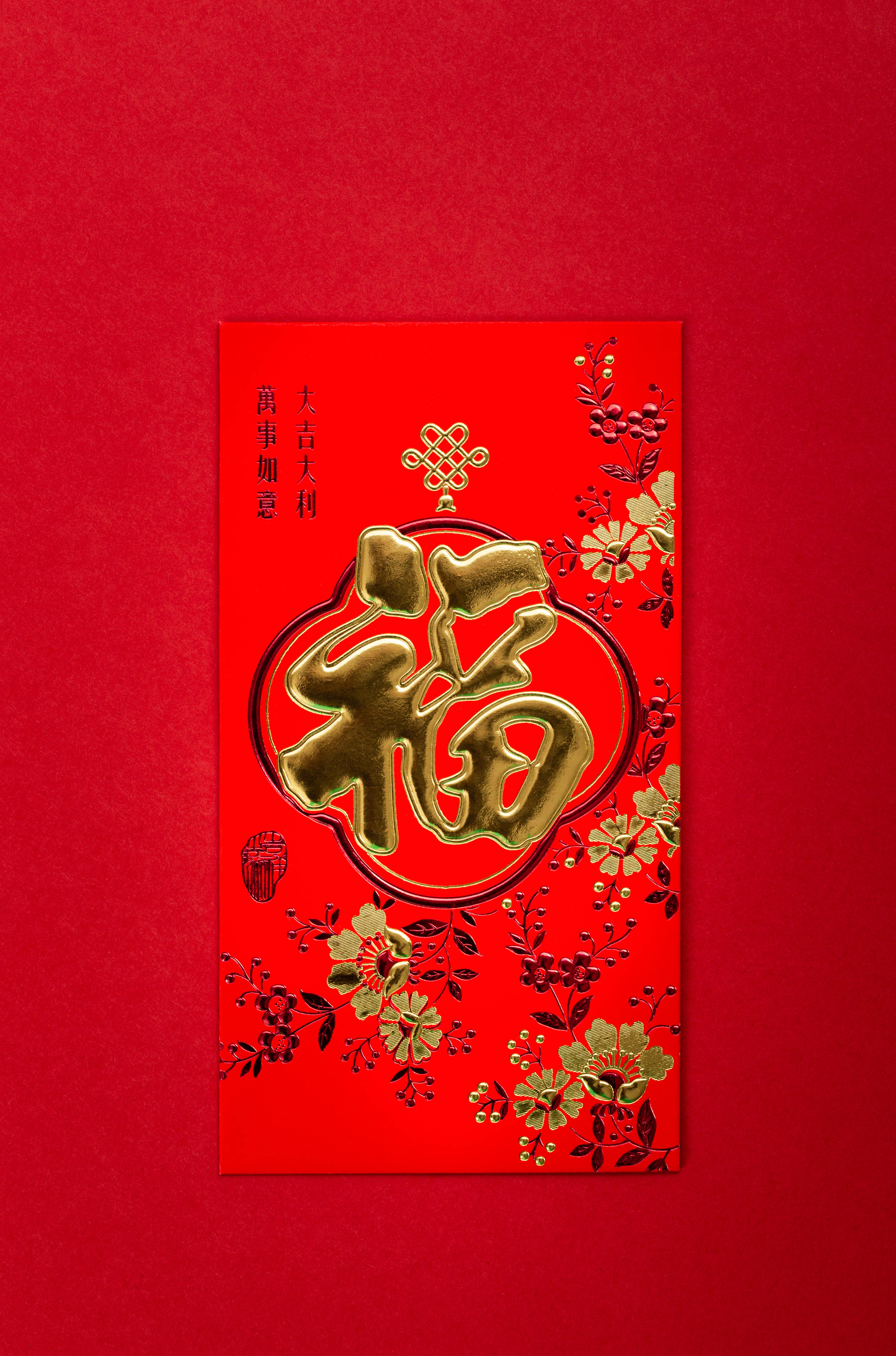 春節 桌布 壁紙 — 一個鮮紅色的中國新年紅包，上面飾有一個大的金色「福」字和花卉圖案，背景為相配的紅色。