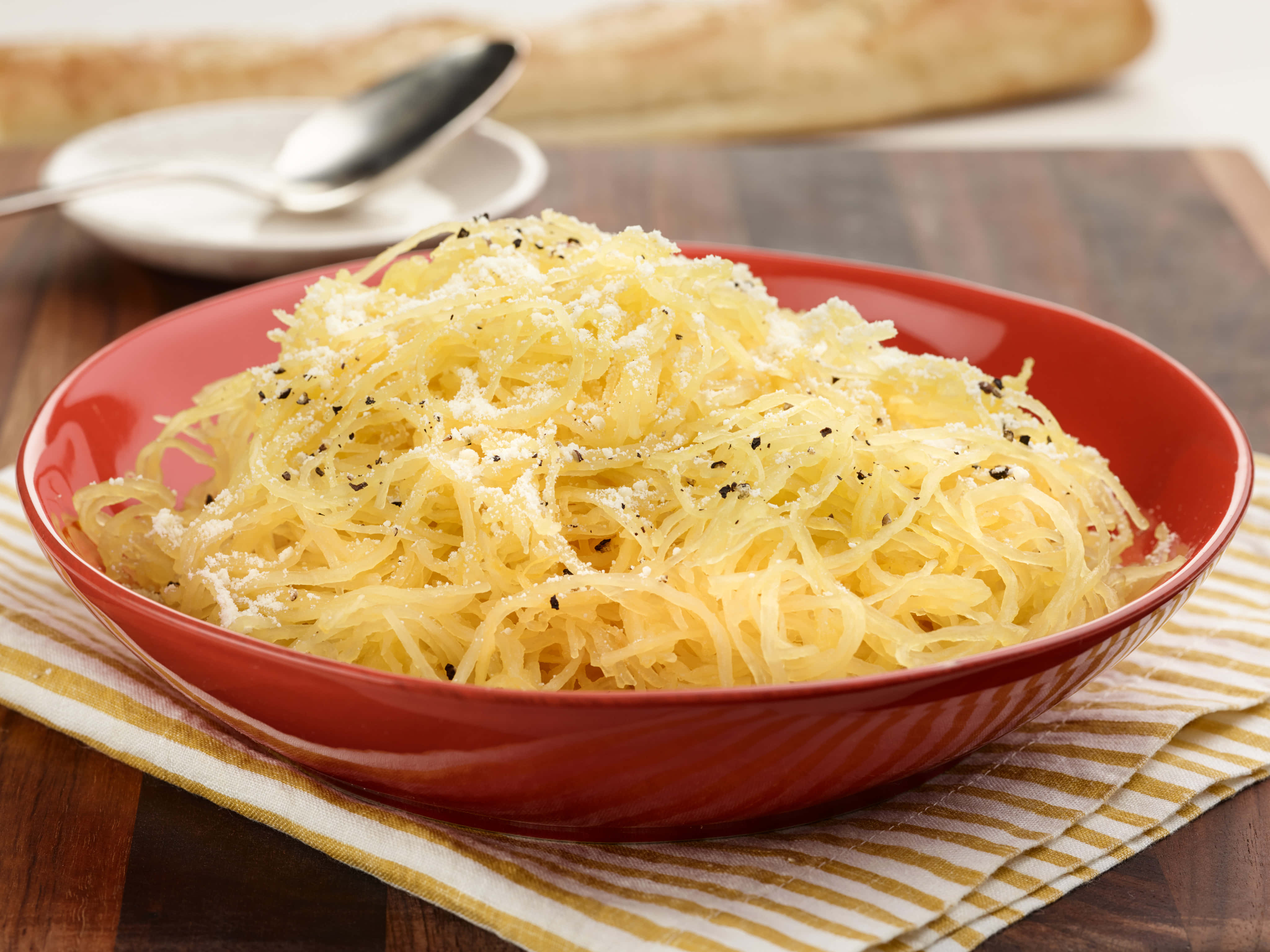 4K Pasta 桌布 壁紙 — 一個鮮紅色的碗，裝滿了奶油般的義式麵條南瓜，上面撒有磨碎的起司和黑胡椒，放在條紋布上。
