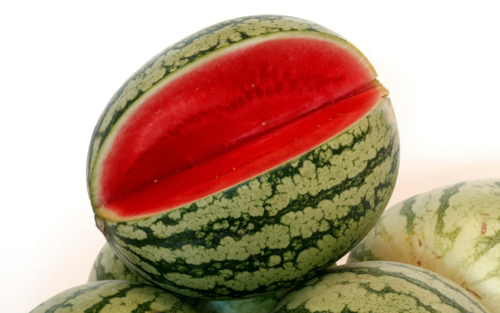 Fruit 桌布 壁紙 — 一個鮮紅色的西瓜切開，露出多汁的果肉，背景是明亮的白色。