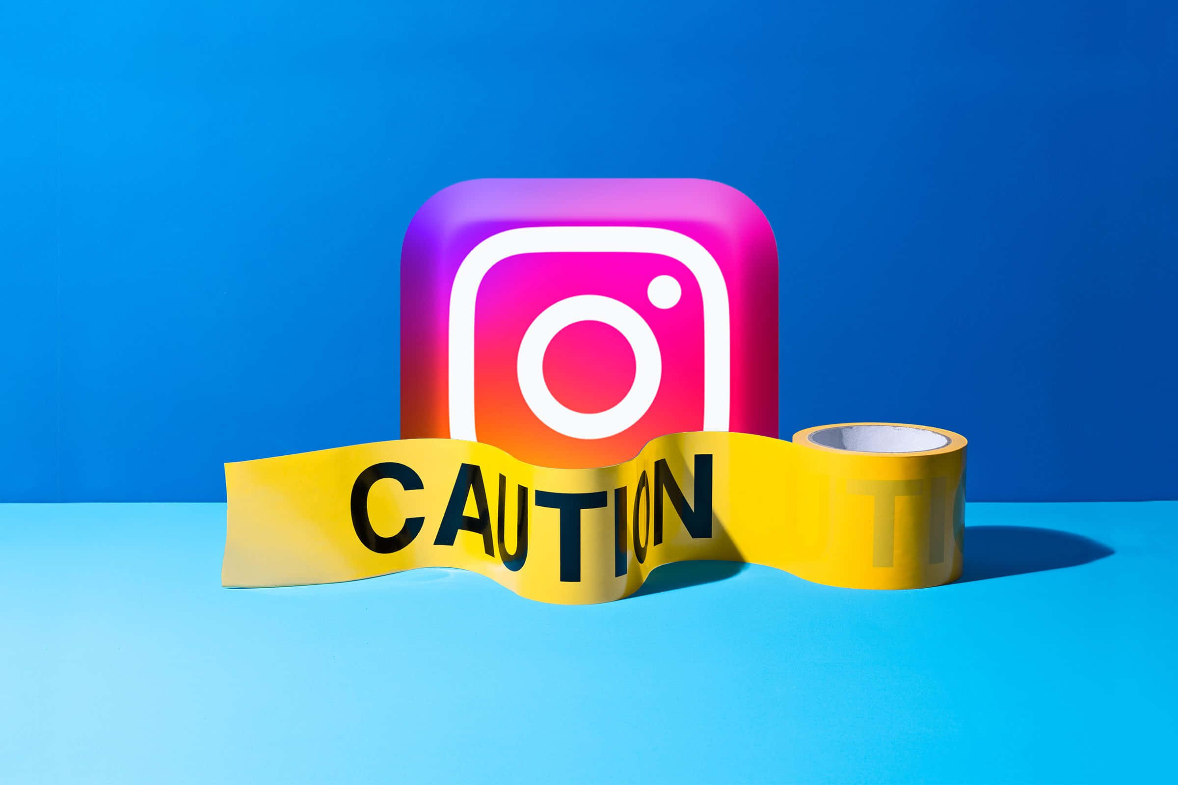 Instagram 桌布 壁紙 — 一個鮮豔的Instagram標誌站在黃色警告膠帶橫幅後面，背景為大膽的藍色。