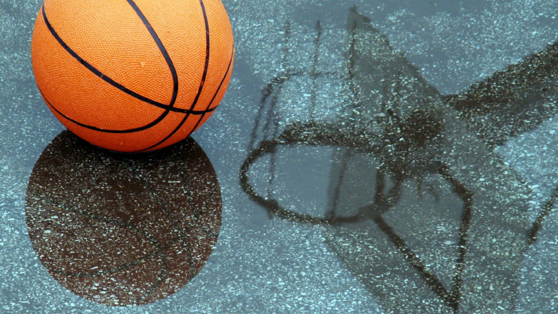 1080p Basketball 桌布 壁紙 — 一個鮮豔的橙色籃球放在濕漉漉的路面上，它的倒影和籃框的影子映照著下方下雨的球場。