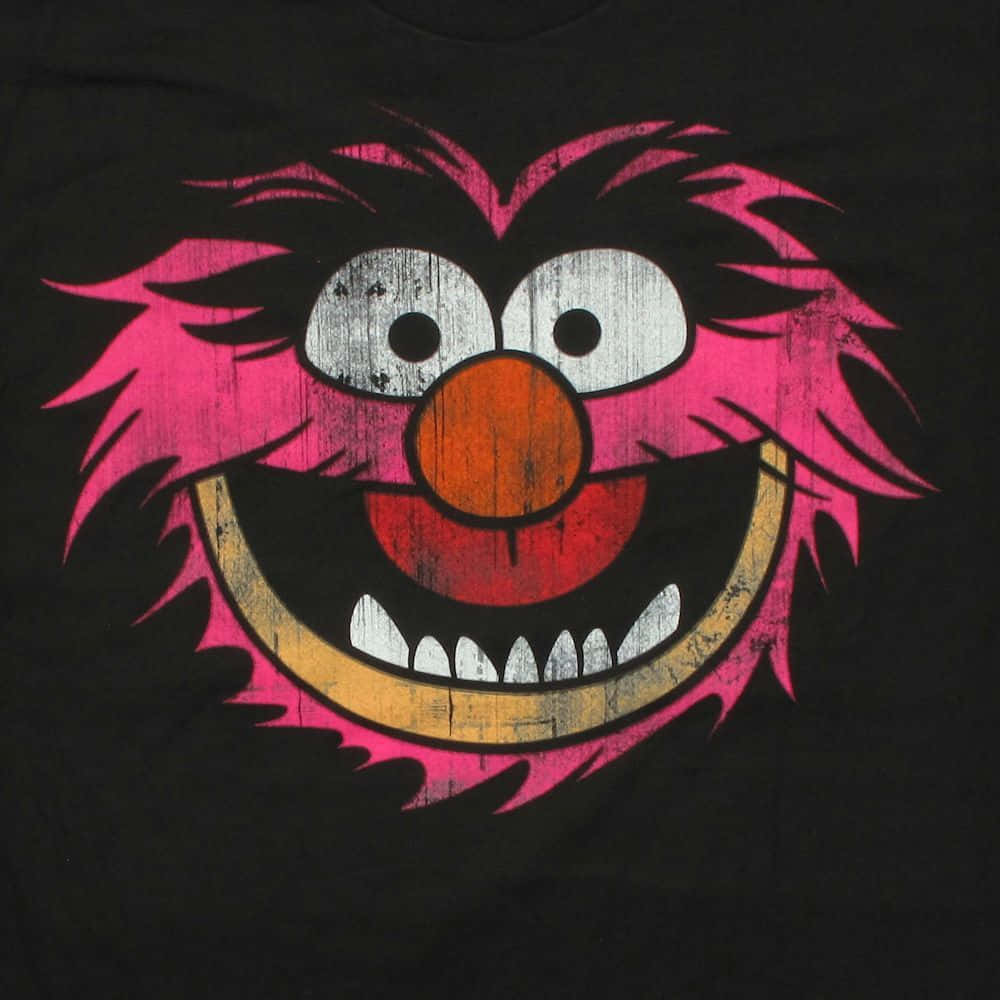 Animal Muppet 桌布 壁紙 — 一個鮮豔的粉紅色毛茸茸怪物臉，張開大嘴露出牙齒的笑容，橙色鼻子，印在黑色T恤上，帶有磨損復古風格。