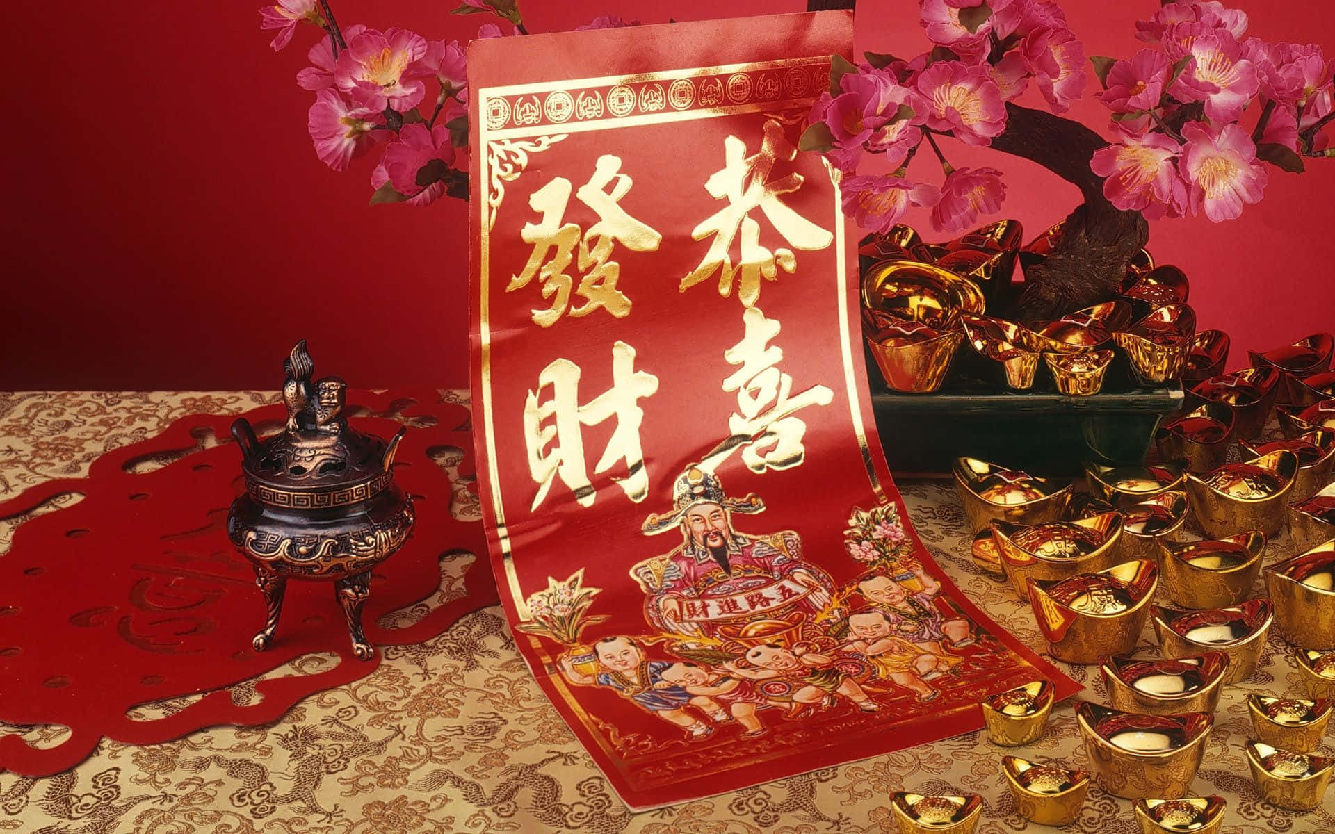 春節 桌布 壁紙 — 一個鮮豔的紅色中國新年橫幅，帶有金色字體和神祇插圖，周圍環繞著金條和粉紅色的花朵。