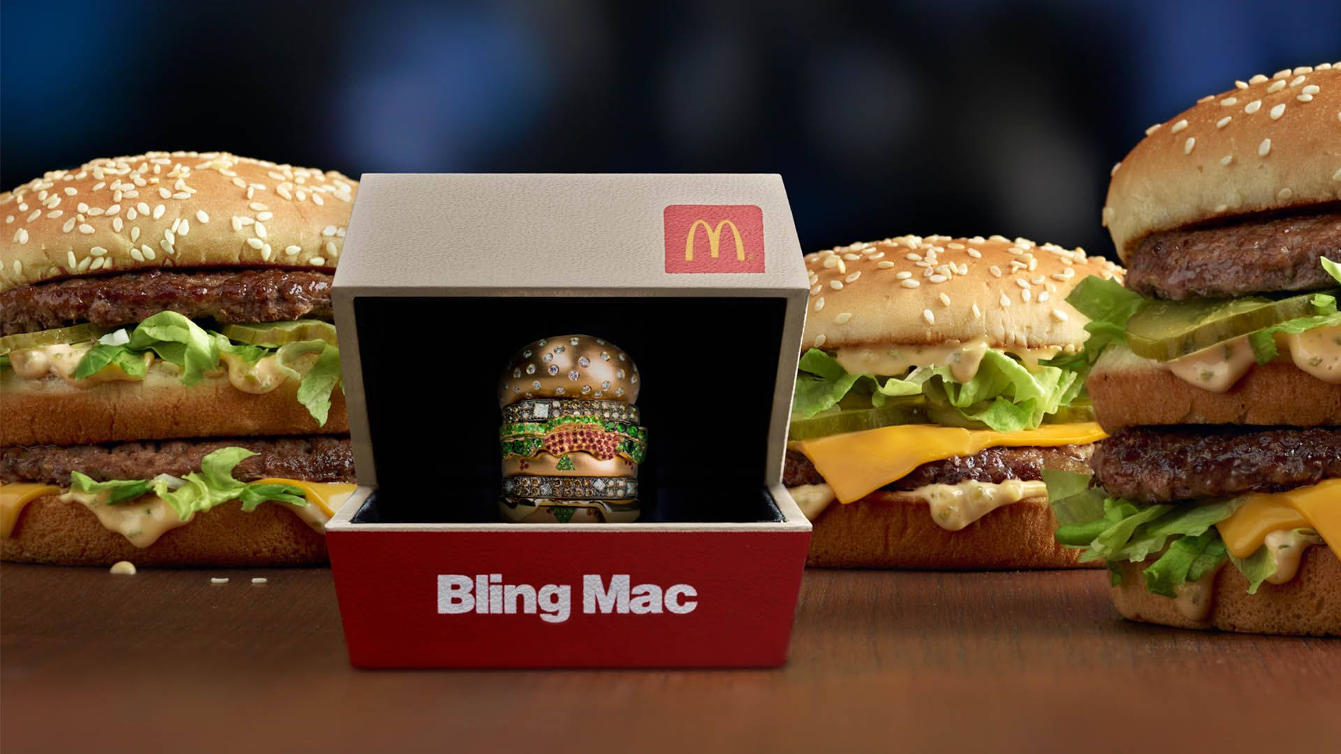 Mcdonalds 桌布 壁紙 — 一個麥當勞Bling Mac漢堡公仔在紅色盒子中閃閃發光，周圍是木桌上的真芝麻漢堡。