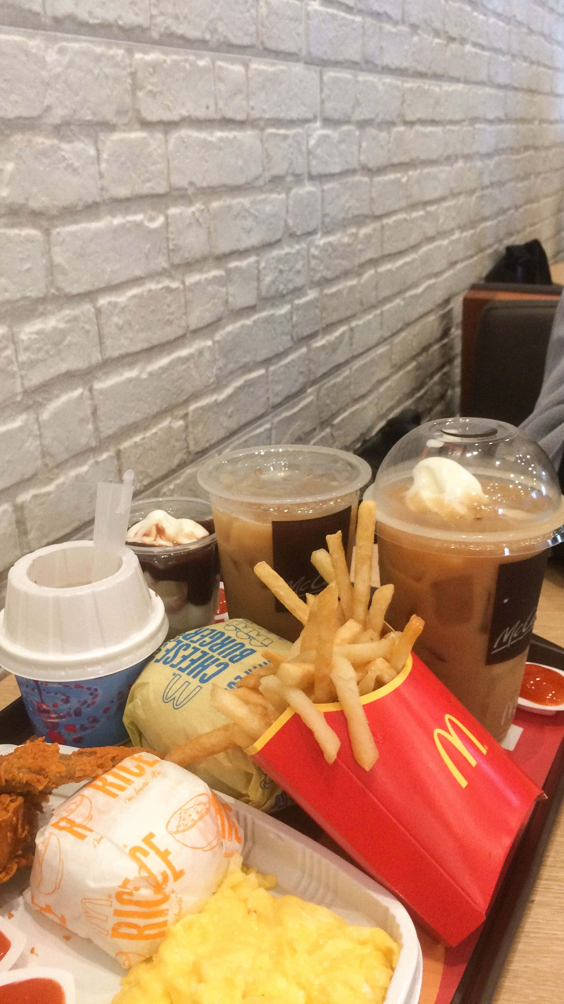 Brick Wall 桌布 壁紙 — 一個麥當勞食物托盤，包括薯條、飲料和漢堡，靠著白色磚牆。
