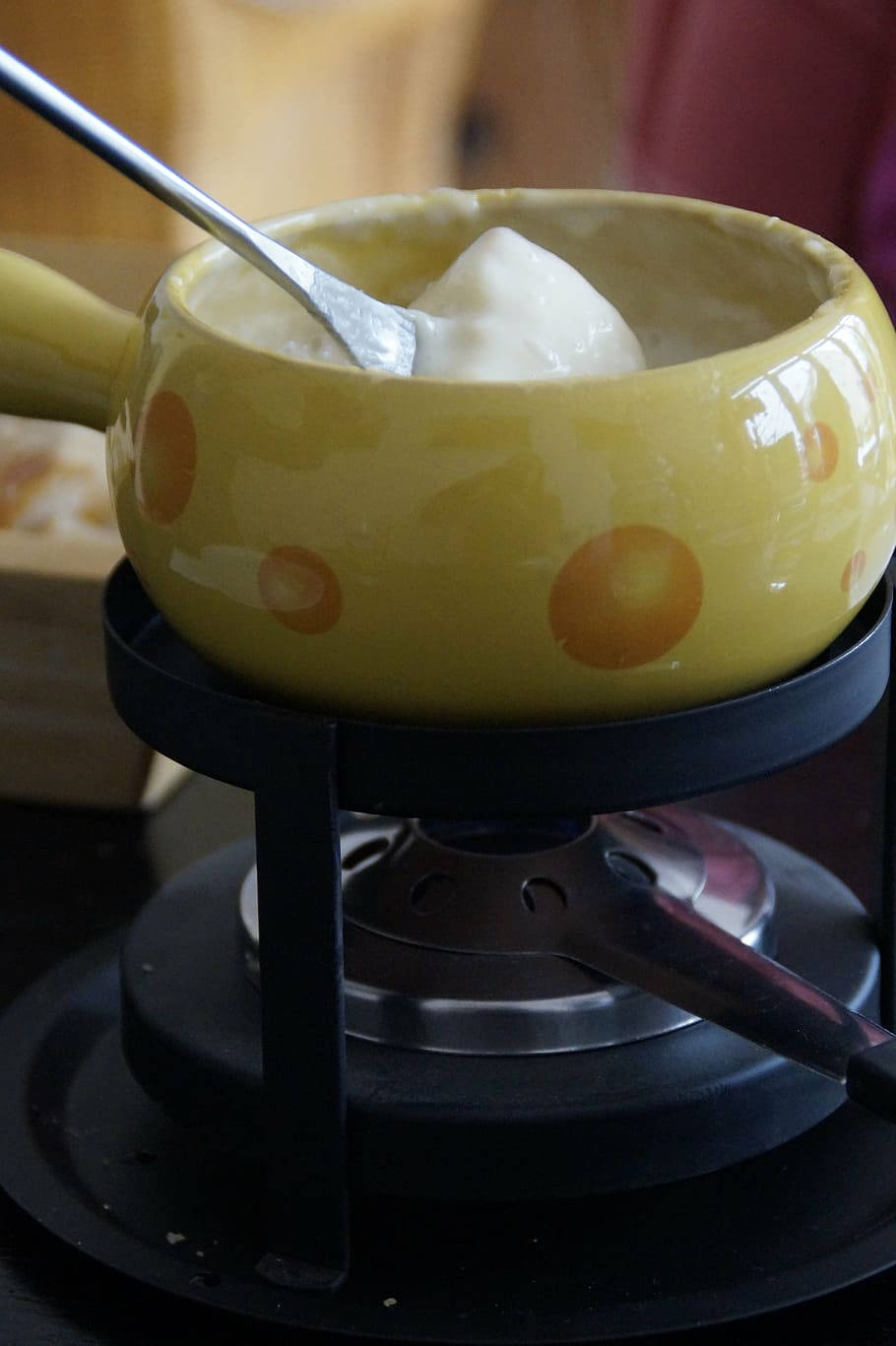 Cheese 桌布 壁紙 — 一個黃色圓點鍋中的奶油起司火鍋在便攜式爐上加熱，一塊麵包塊正在蘸取。