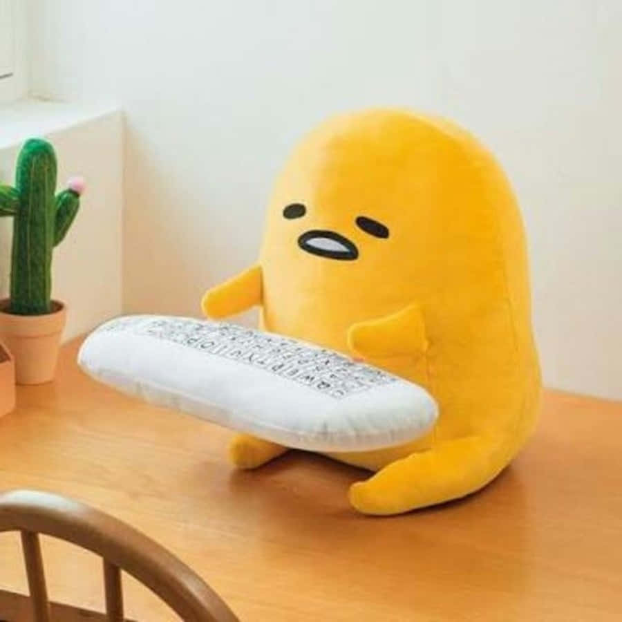 黃色 Gudetama 絨毛玩具在木桌上抱著枕頭，旁邊有仙人掌。 — 蛋黃哥 壁紙