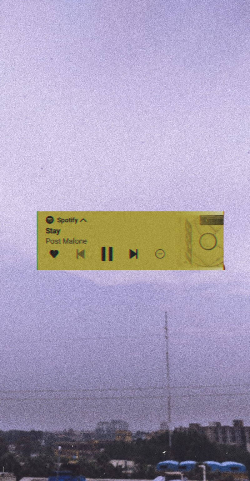 音樂美學 桌布 壁紙 — 一個黃色的Spotify音樂播放器漂浮在朦朧的紫色天空中，背景是遙遠的城市景觀。