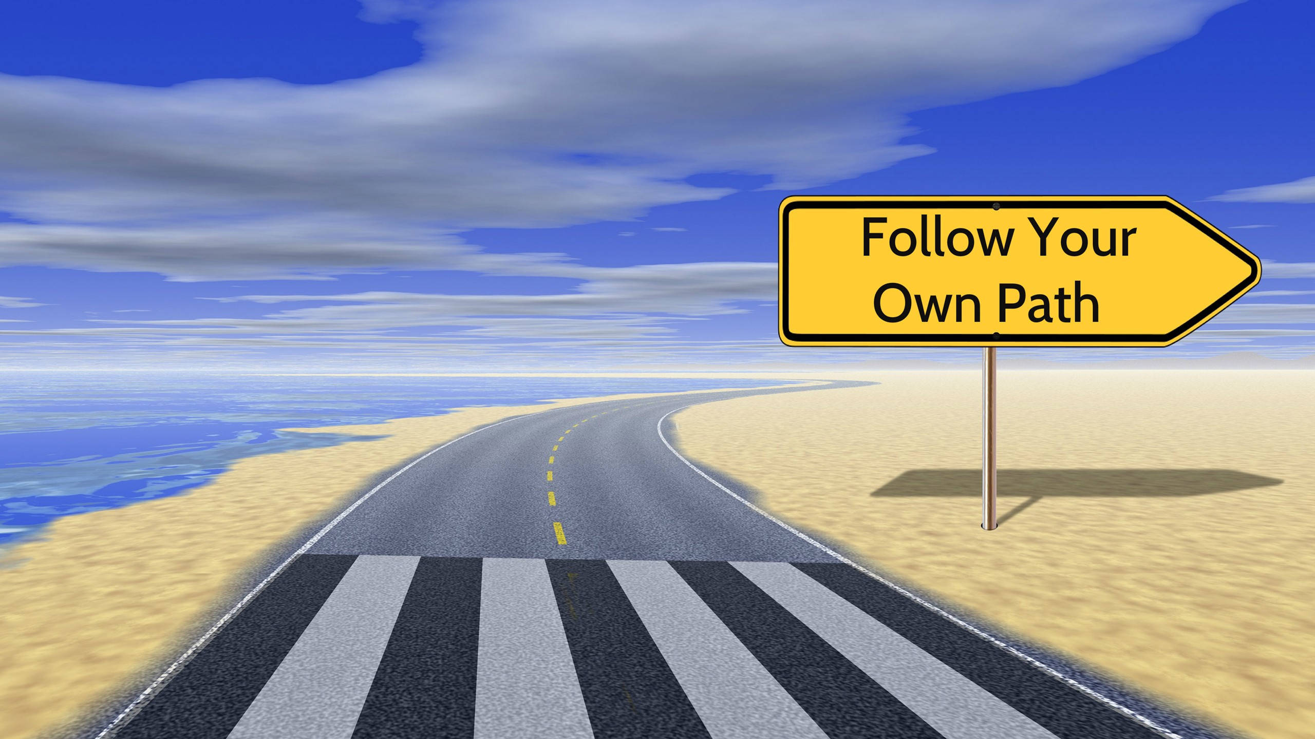 HD inspirational 桌布 壁紙 — 一個黃色路牌寫著「Follow Your Own Path」，矗立在藍天白雲下穿過沙漠的蜿蜒柏油道路旁。