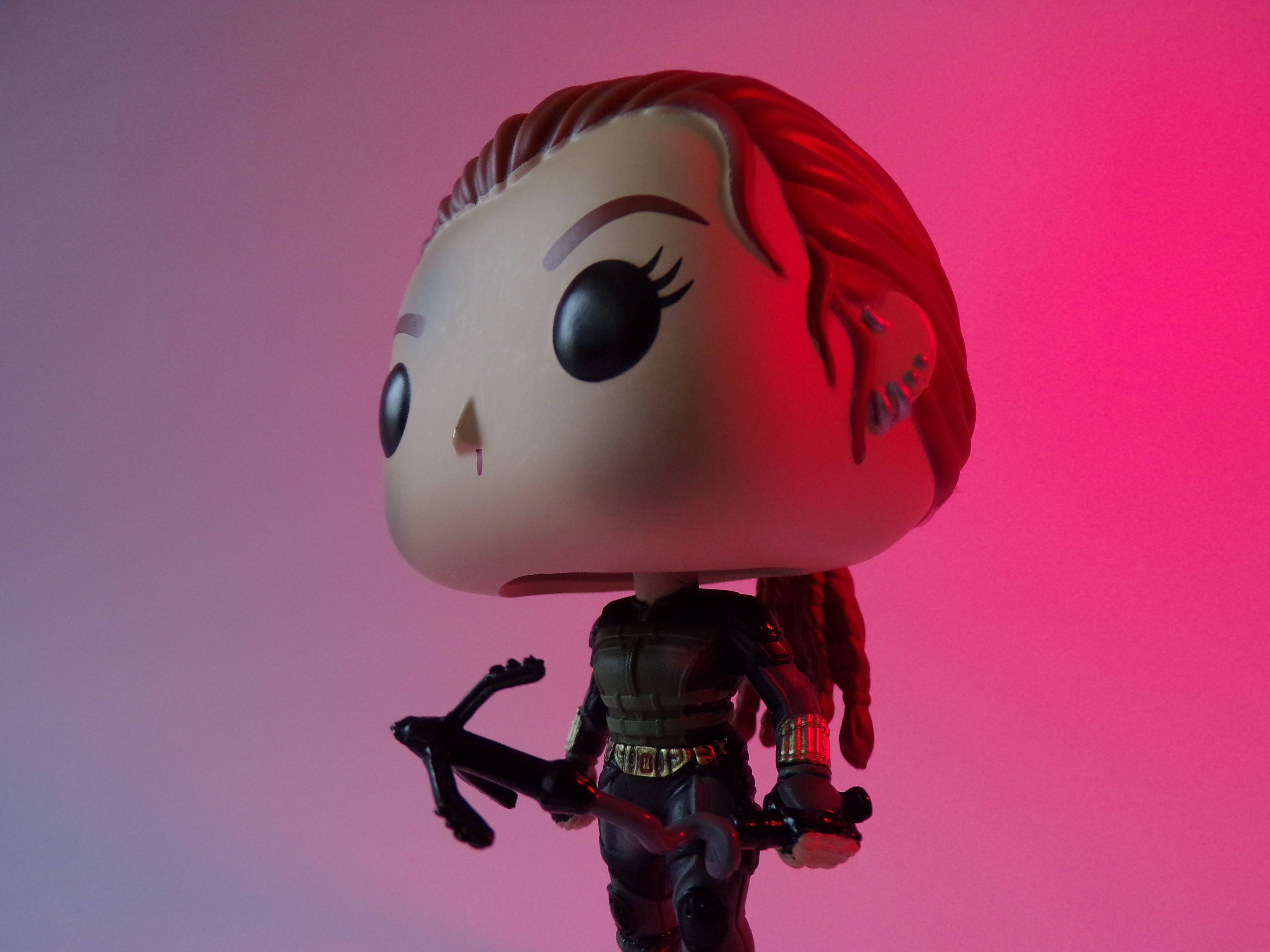 Funko Pop 桌布 壁紙 — 一個黑寡婦的Funko Pop人偶在戲劇性的粉紅和紫色燈光下站立，手持弓箭。