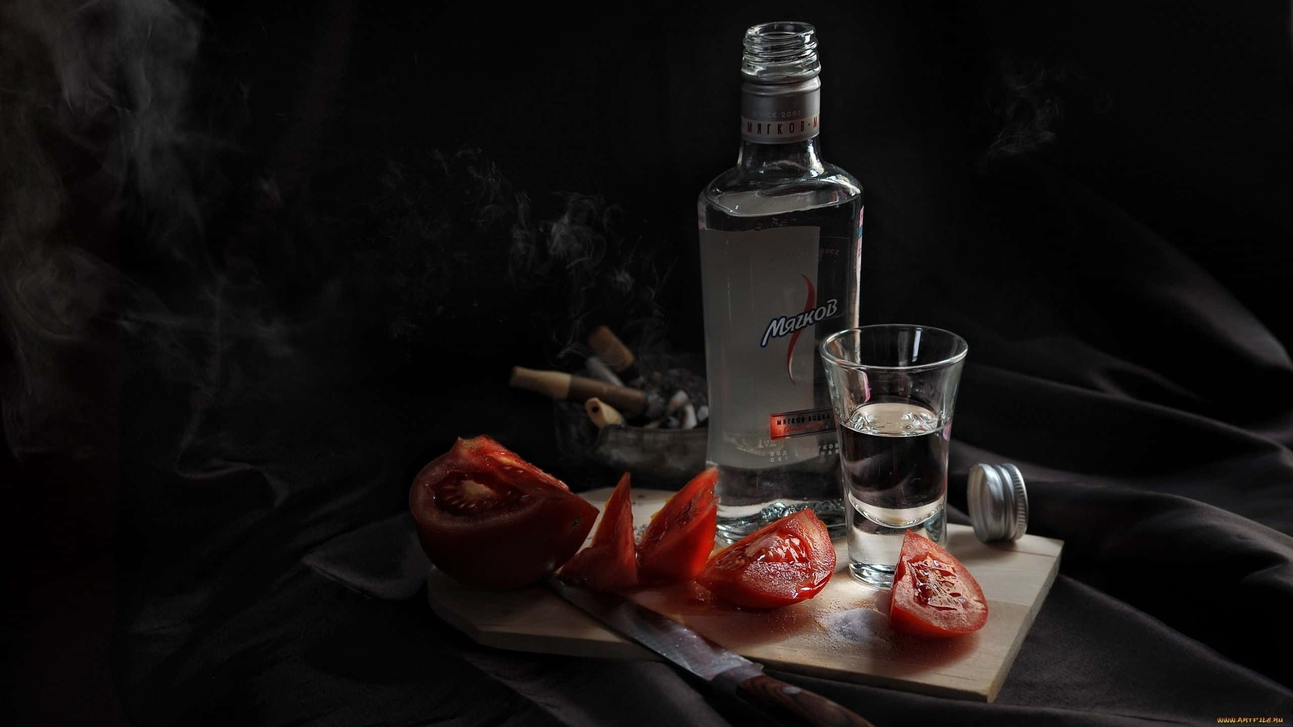 alcohol 桌布 壁紙 — 一個黑暗的靜物構圖，包含伏特加酒瓶、玻璃杯和切片番茄放在木板上，煙霧在黑色背景下升起。