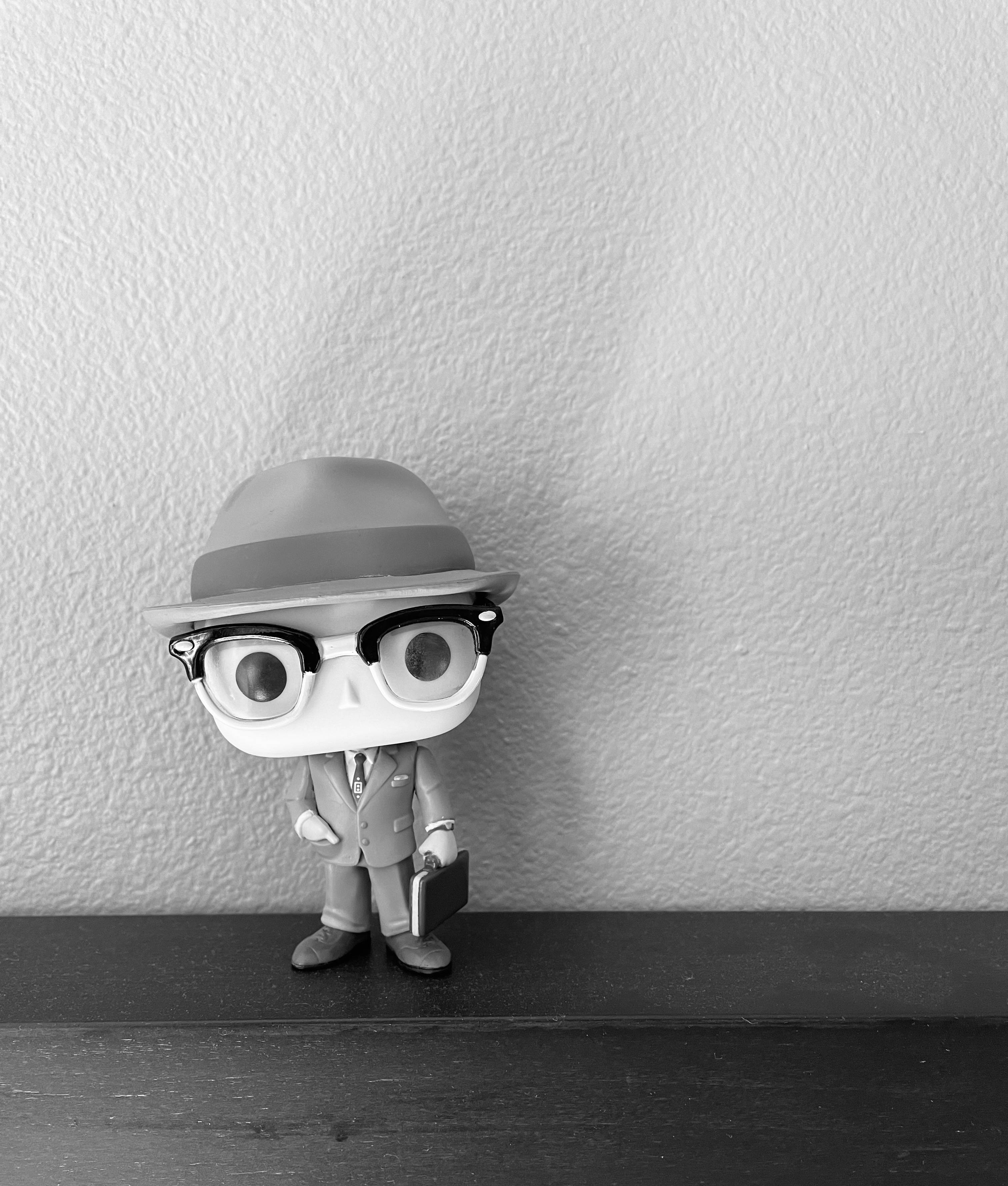 Wandavision 桌布 壁紙 — 一個黑白Funko Pop公仔，身穿西裝、戴帽和眼鏡，站在一個有紋理牆壁的架子上。