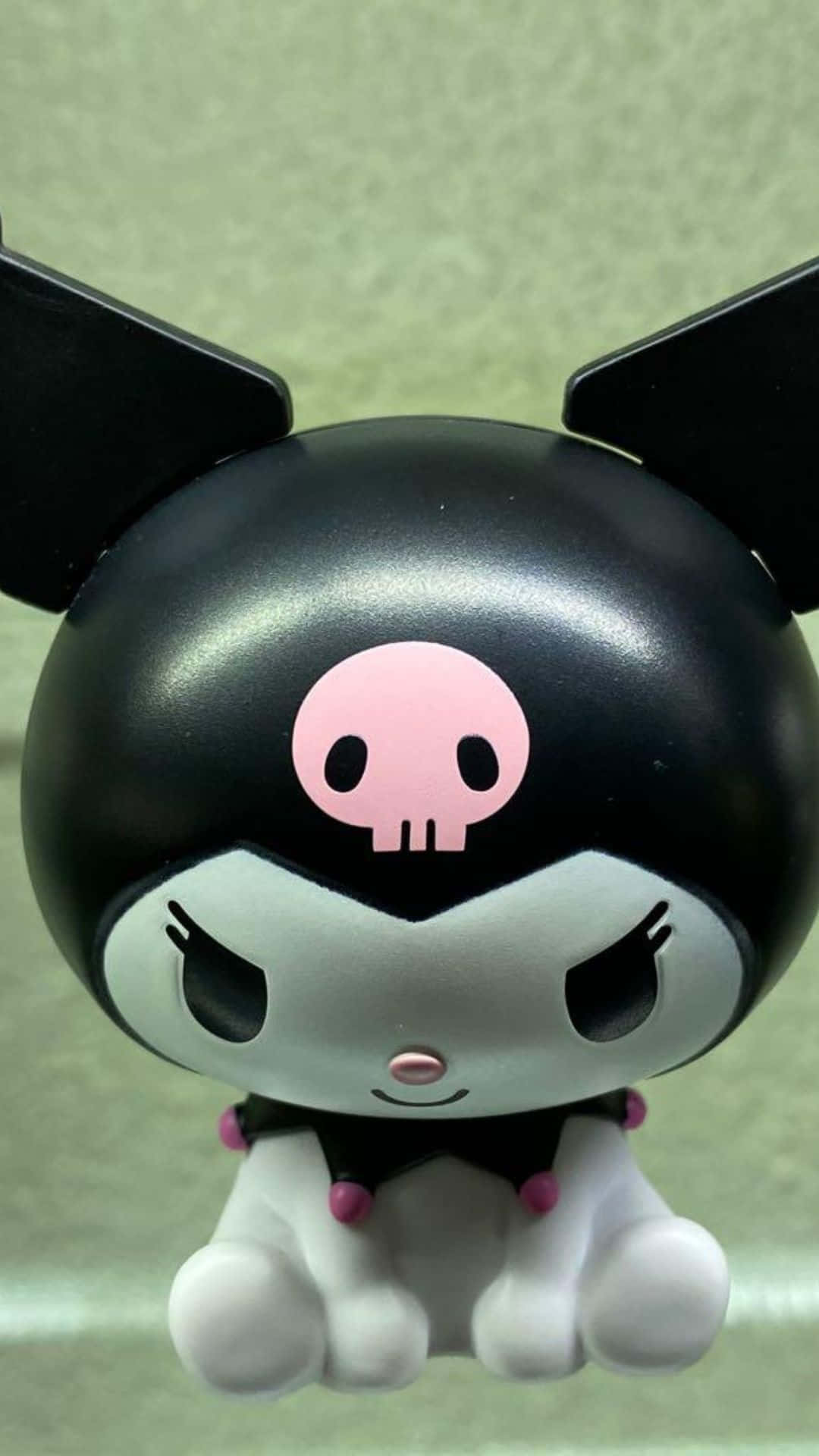 Bandai 桌布 壁紙 — 一個黑白Kuromi公仔的特寫，帶有粉紅色骷髏標誌和憤怒的眼睛，背景為柔和的綠色。