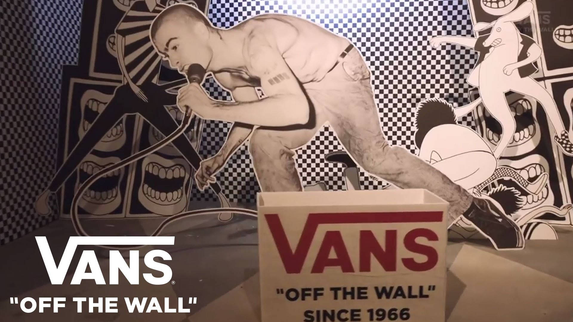 Vans Off The Wall 桌布 壁紙 — 一個黑白剪影的歌手拿著麥克風，站在一面帶有尖叫嘴巴和格子圖案的塗鴉風格牆前。