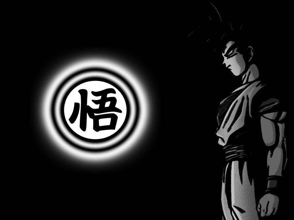 Black Goku 桌布 壁紙 — 一個黑白動漫角色站在一個發光的圓形徽章旁邊，徽章上有一個漢字，背景為深色。