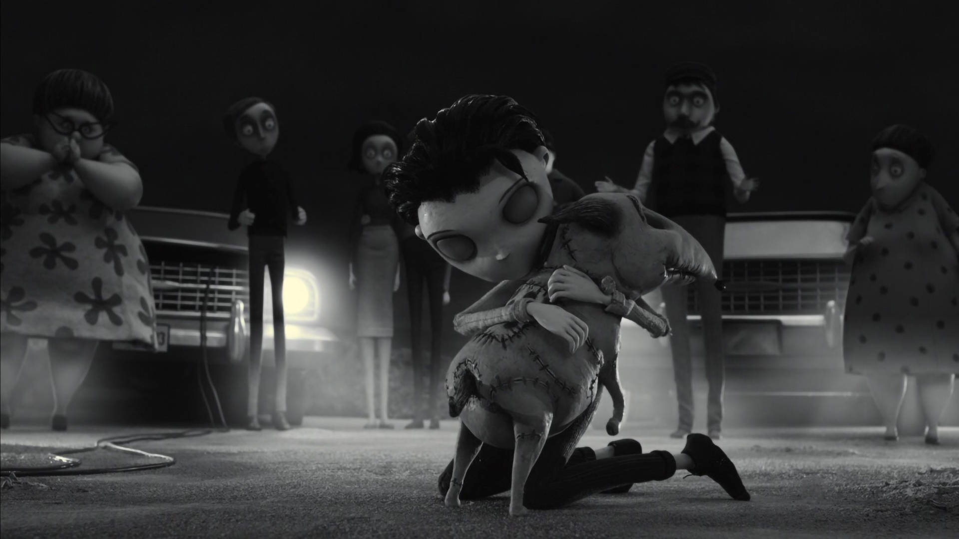 Frankenweenie 桌布 壁紙 — 一個黑白動畫場景顯示一個男孩跪著擁抱一個縫製的娃娃，而詭異的人物站在背景中靠近復古汽車。