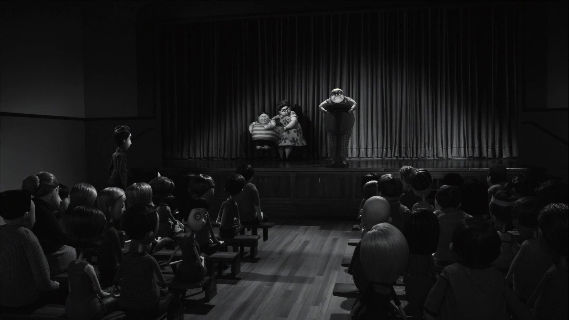Frankenweenie 桌布 壁紙 — 一個黑白動畫場景顯示三位表演者在有窗簾的舞台上表演，觀眾從木長凳上觀看。