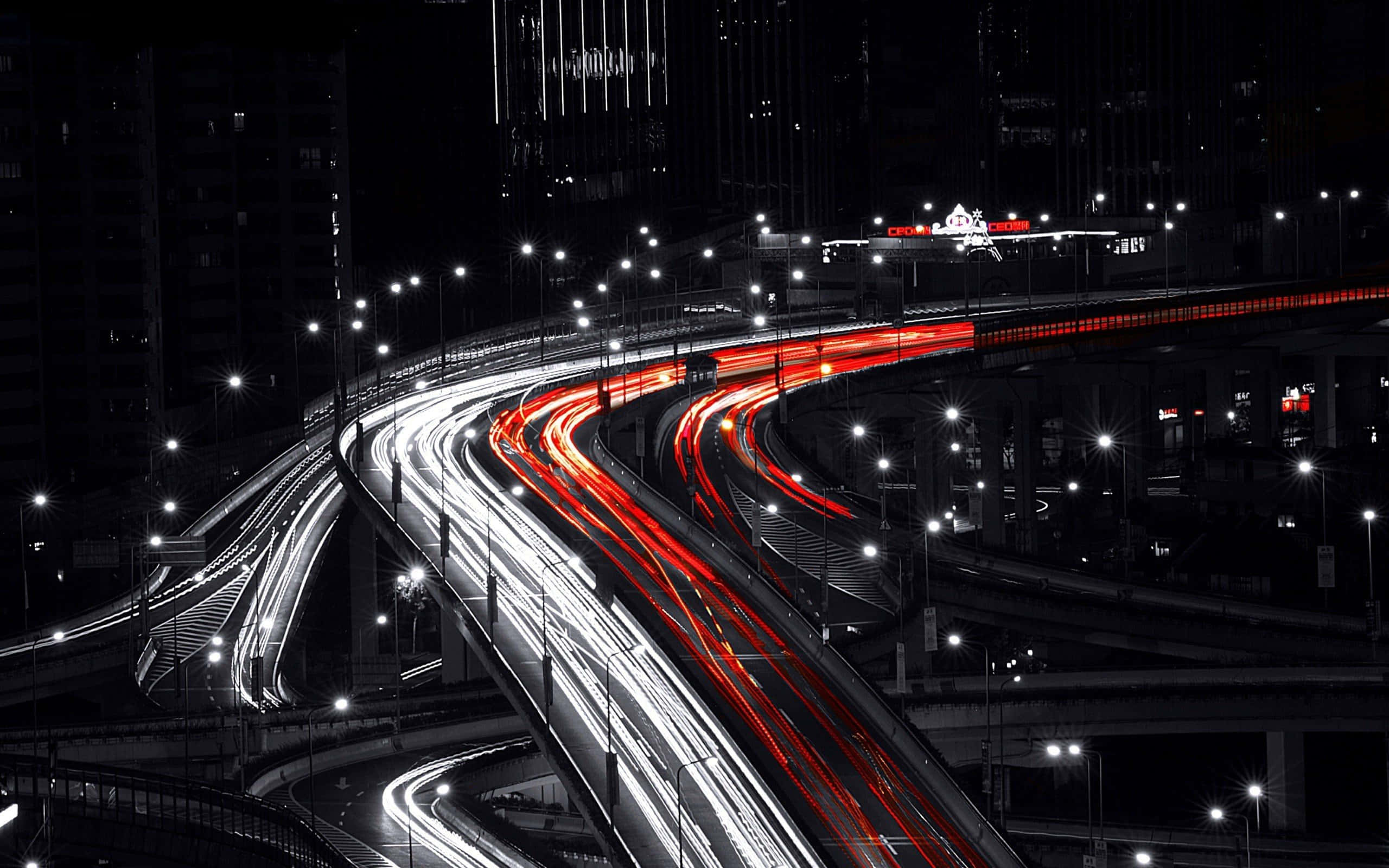 Red White And Black Abstract 桌布 壁紙 — 一個黑白夜景城市景觀，複雜高速公路交匯處的交通留下鮮豔的紅色和白色光軌。