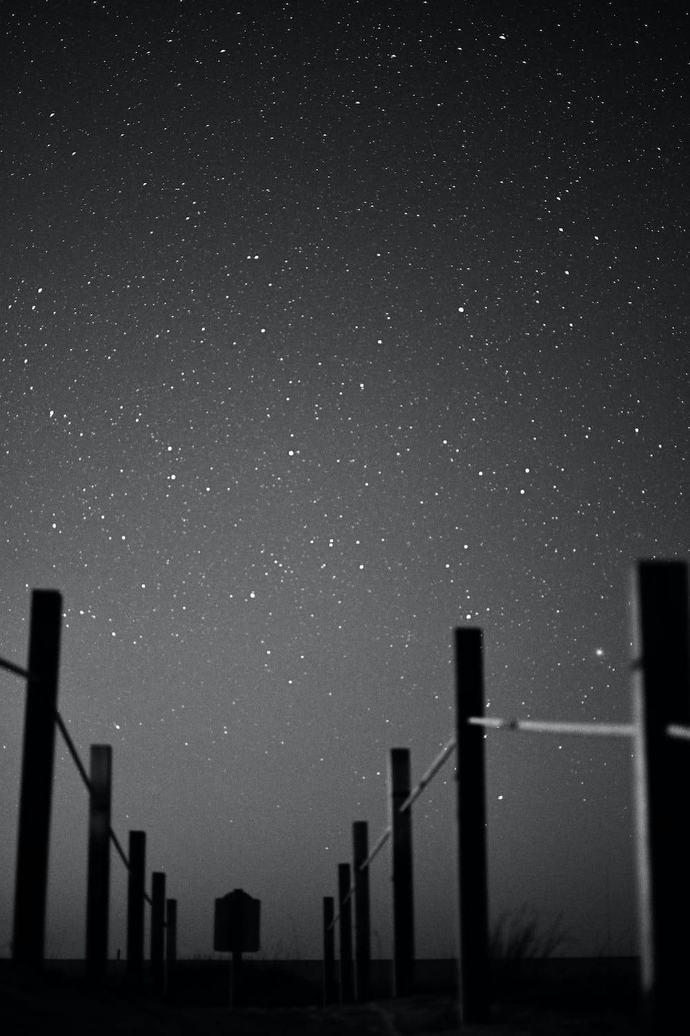 木紋 桌布 壁紙 — 一個黑白夜空，充滿無數星星，由籬笆柱的黑暗剪影框住。