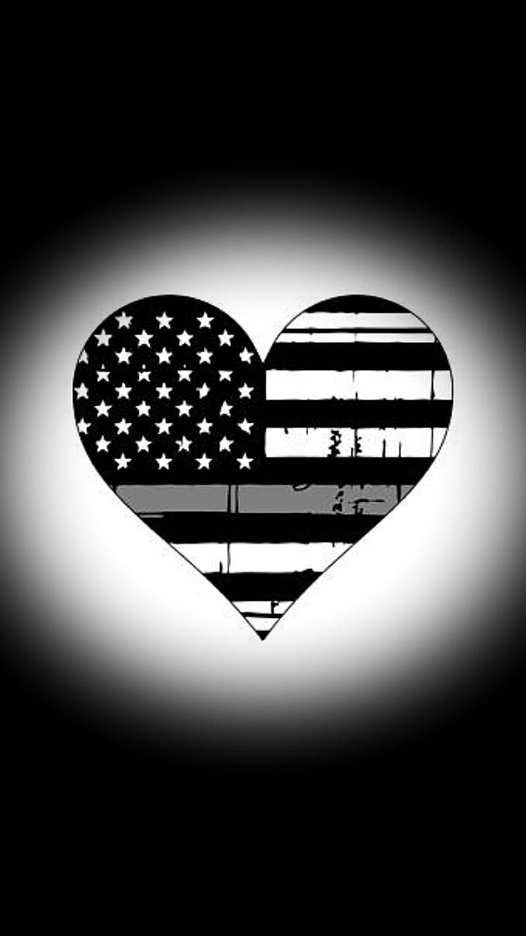 Black American Flag 桌布 壁紙 — 一個黑白心形美國國旗，帶有磨損紋理，在黑暗背景中置於發光聚光燈中央。