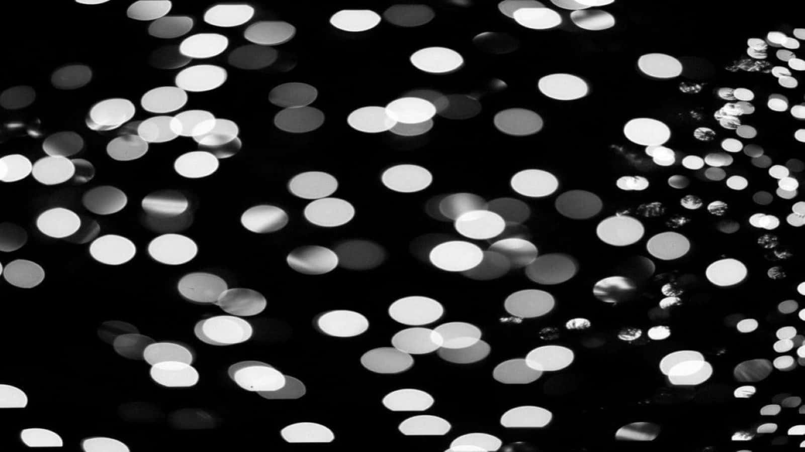 Black And White Dots 桌布 壁紙 — 一個黑白抽象圖案，發光的圓形散景燈光散落在深色背景上。