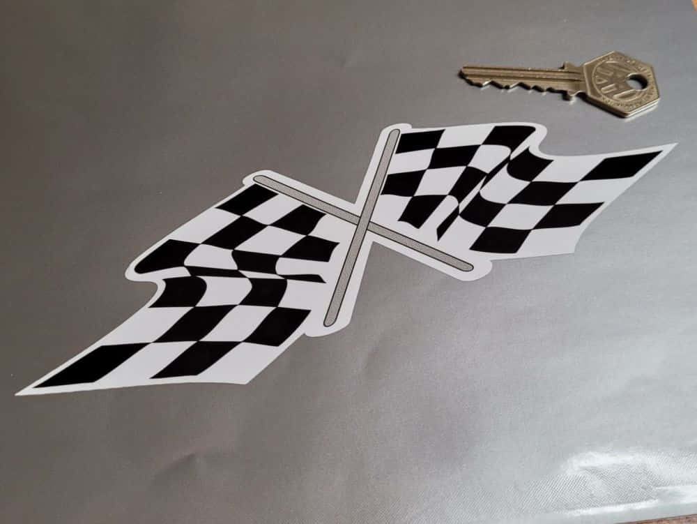 Chequered Flag 桌布 壁紙 — 一個黑白格紋賽車旗翼形貼紙放在銀色表面上的一個金屬鑰匙旁邊。